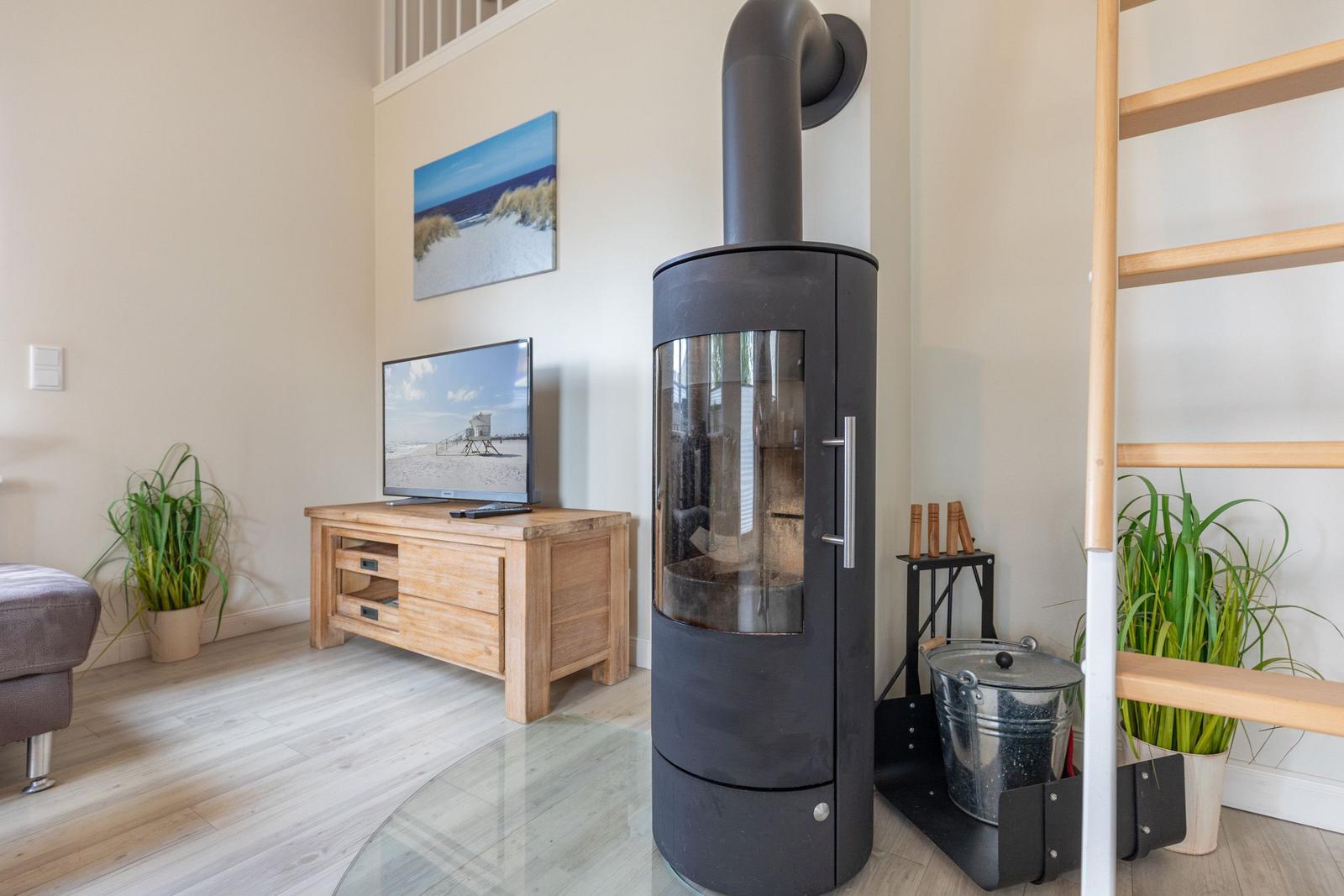 Wohnzimmer mit Kaminofen, Fernseher und Pflanzen.