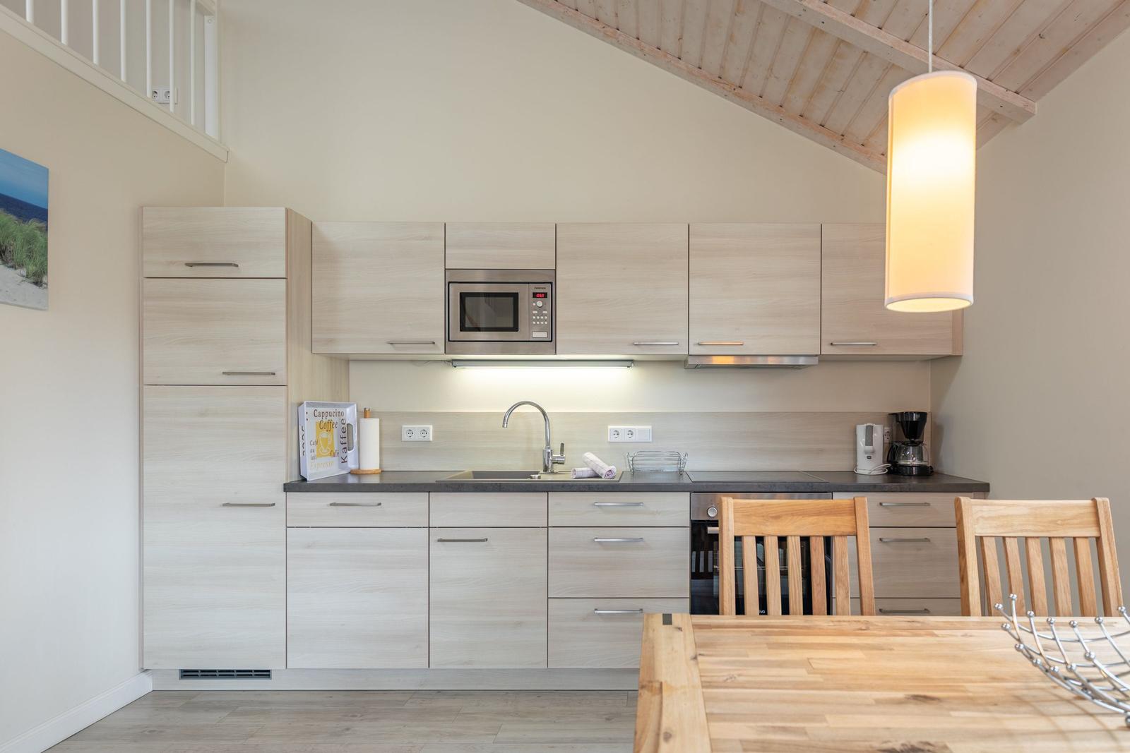 Küche mit Holzmöbeln, Spüle, Mikrowelle und Esstisch