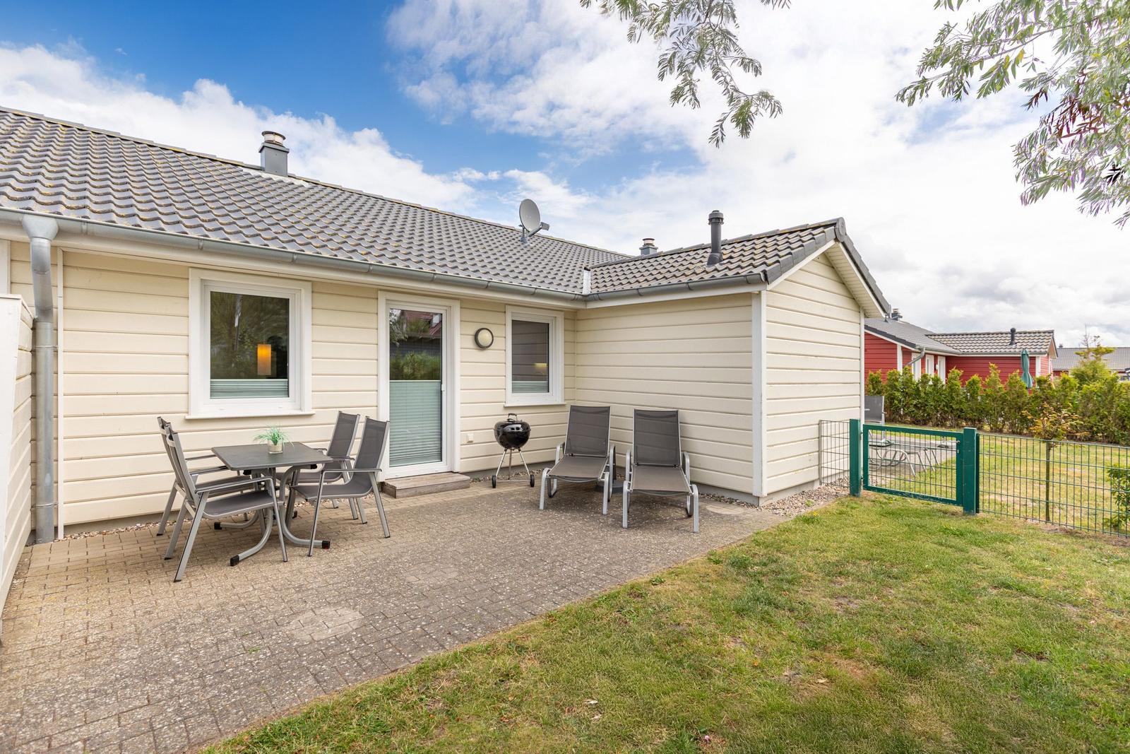 Haus mit Terrasse, Grill und Garten. Außenbereich mit Sitzgelegenheiten.