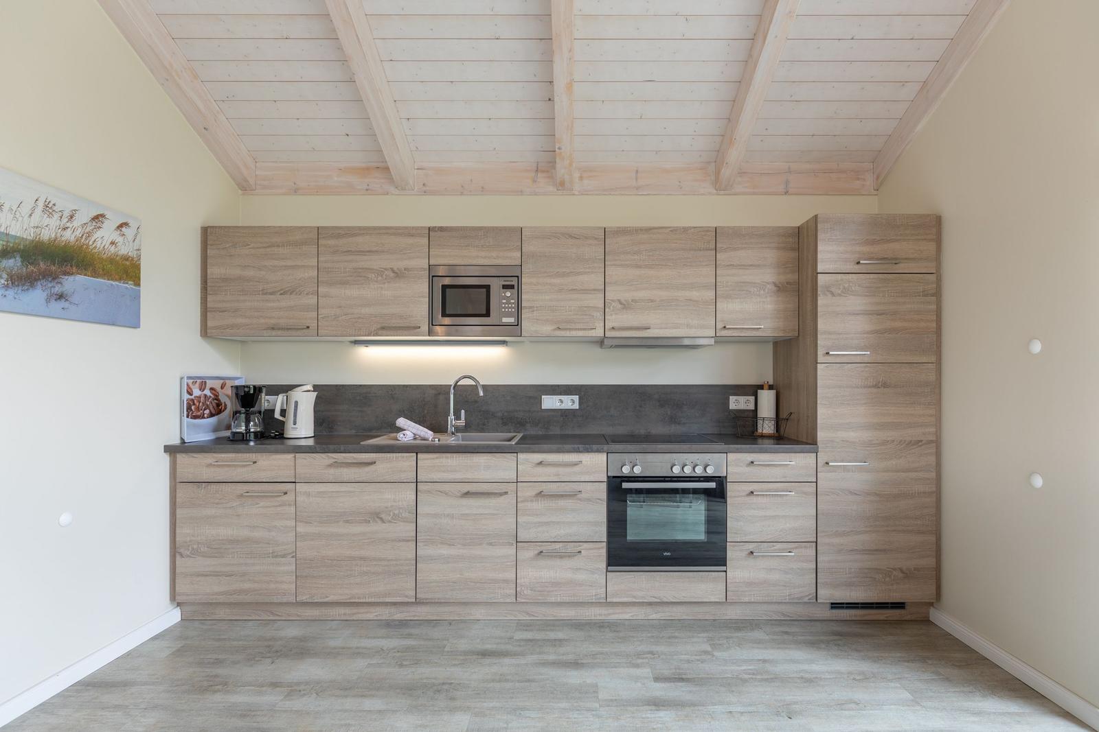 Küche mit Holzdecke, Edelstahlgeräten und Holzschränken.