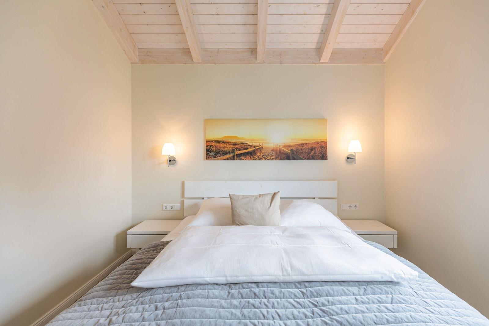 Schlafzimmer mit Bett, Nachttischen und Wandbild.