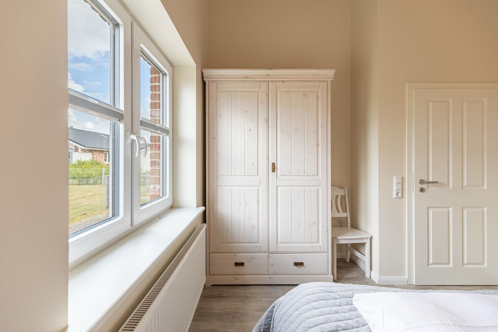 Schlafzimmer mit Fenster, Kleiderschrank und Tür.