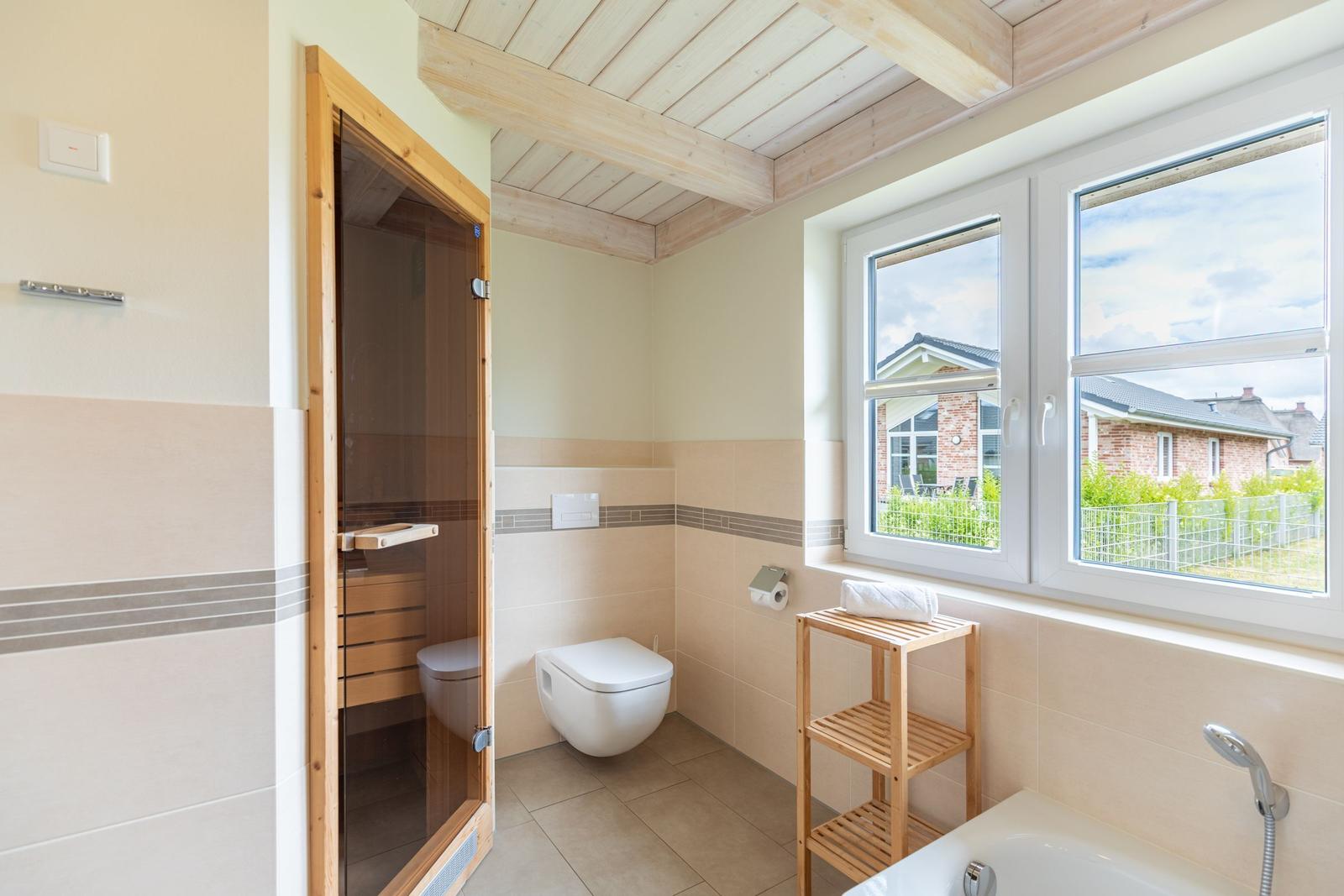 Badezimmer mit Sauna, Toilette, Badewanne und Fenster mit Blick.