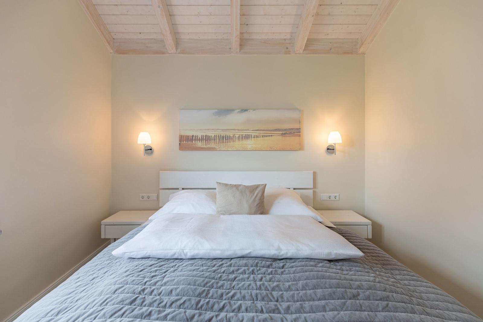 Schlafzimmer mit Bett, Nachttischen und Wandbild.