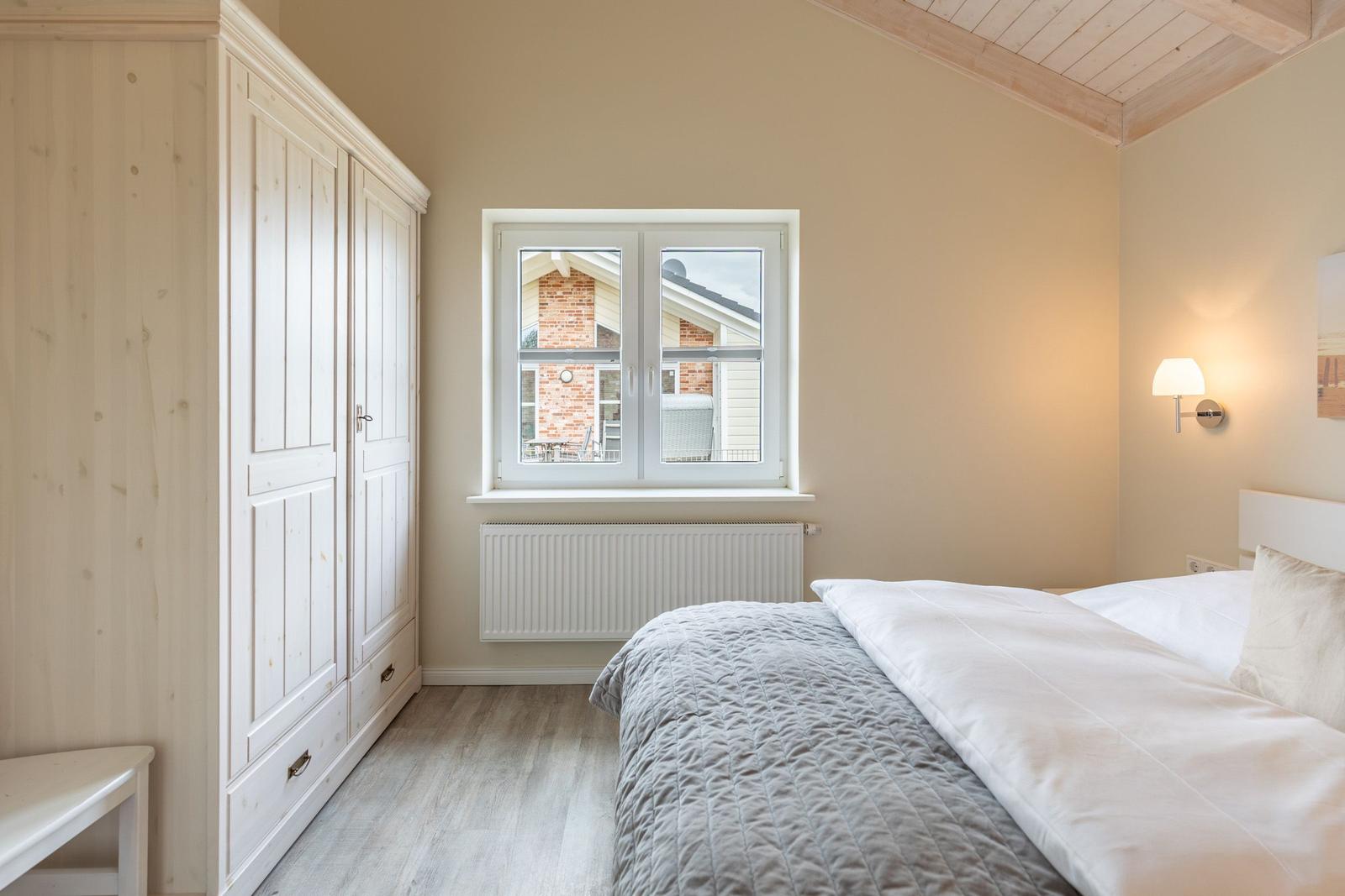 Schlafzimmer mit Doppelbett, Kleiderschrank und Fenster zur Außenseite.