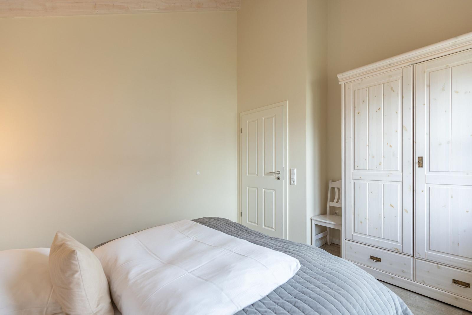Schlafzimmer mit Bett, Kleiderschrank und Tür.