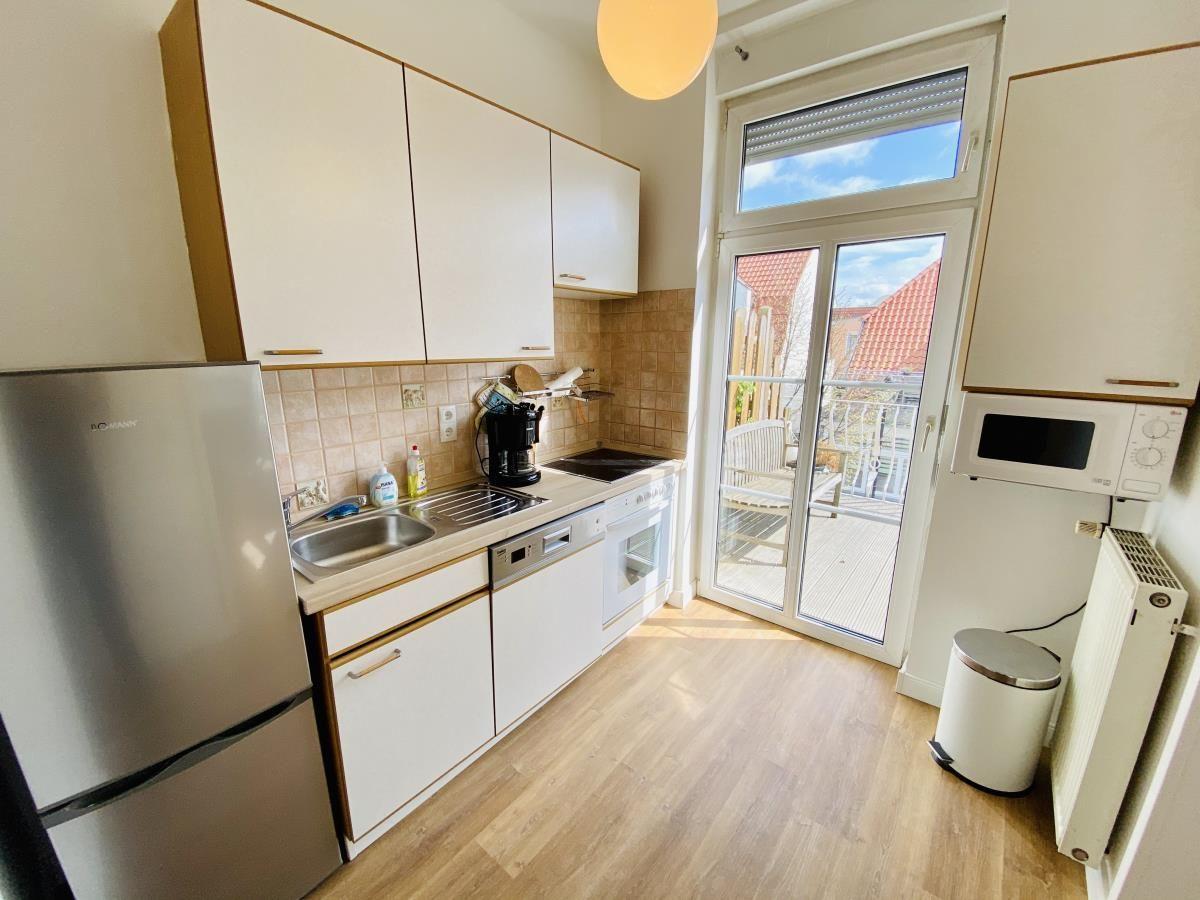 Küche mit Kühlschrank, Spüle und Fenster zur Terrasse.