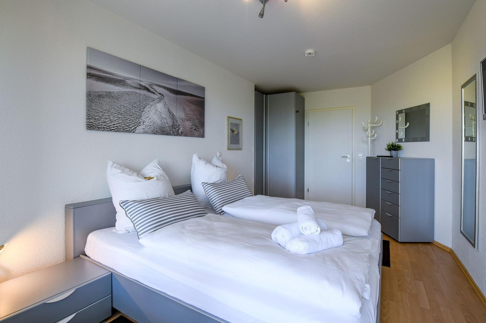 Schlafzimmer mit Doppelbett, Kleiderschrank und Spiegelschrank.