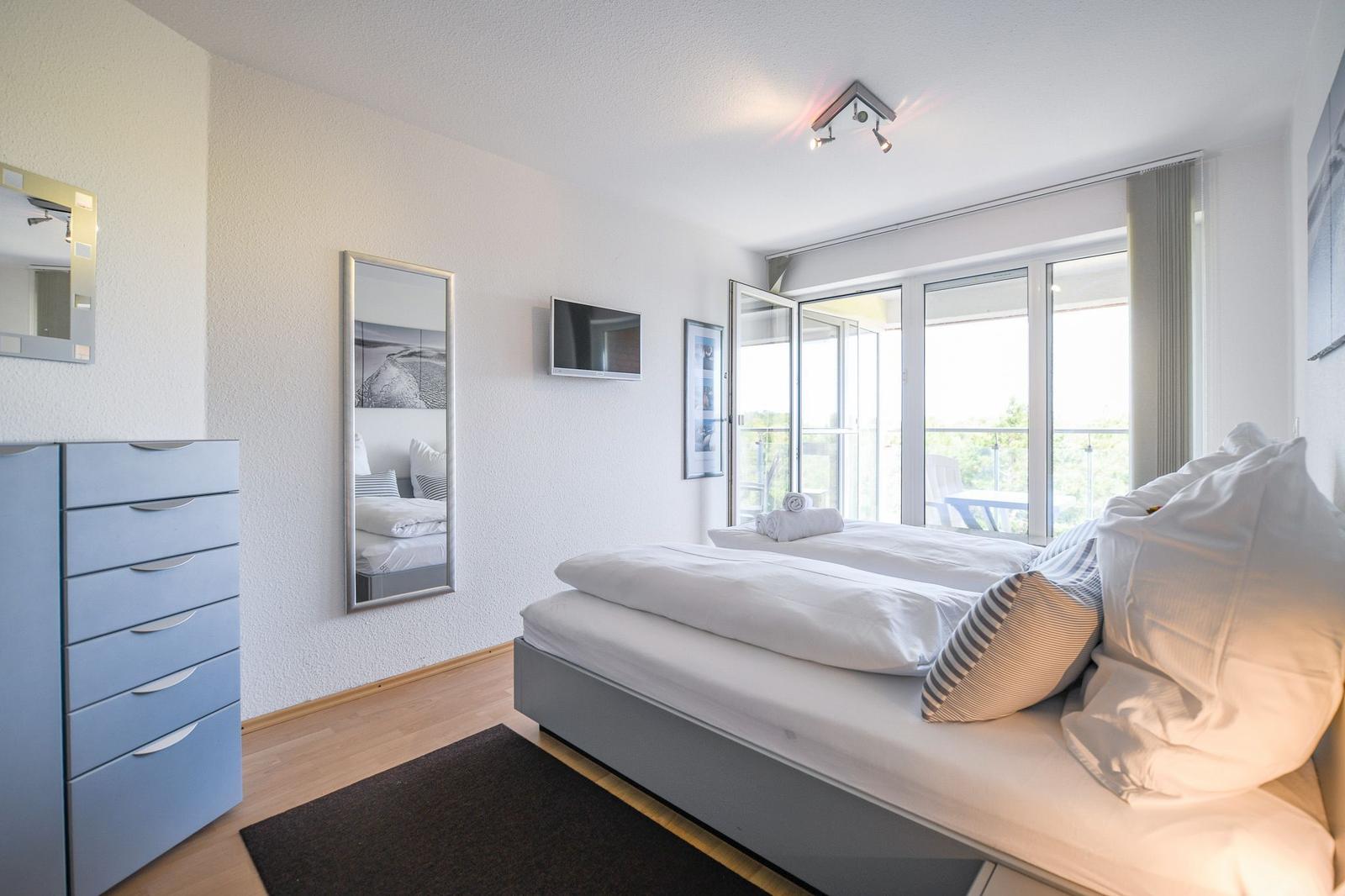 Schlafzimmer mit Doppelbett, Schrank und Balkonzugang.
