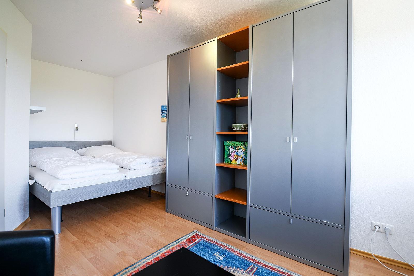 Schlafzimmer mit Doppelbett und Kleiderschrank mit Regalen.