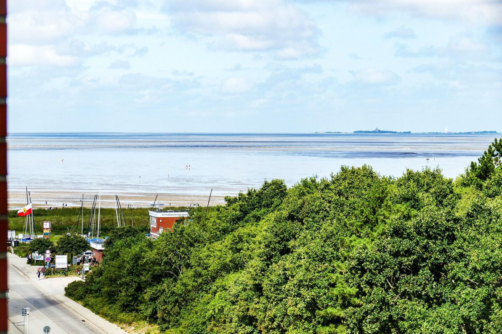 Meeresblick mit Strand, Booten und grüner Vegetation im Vordergrund.