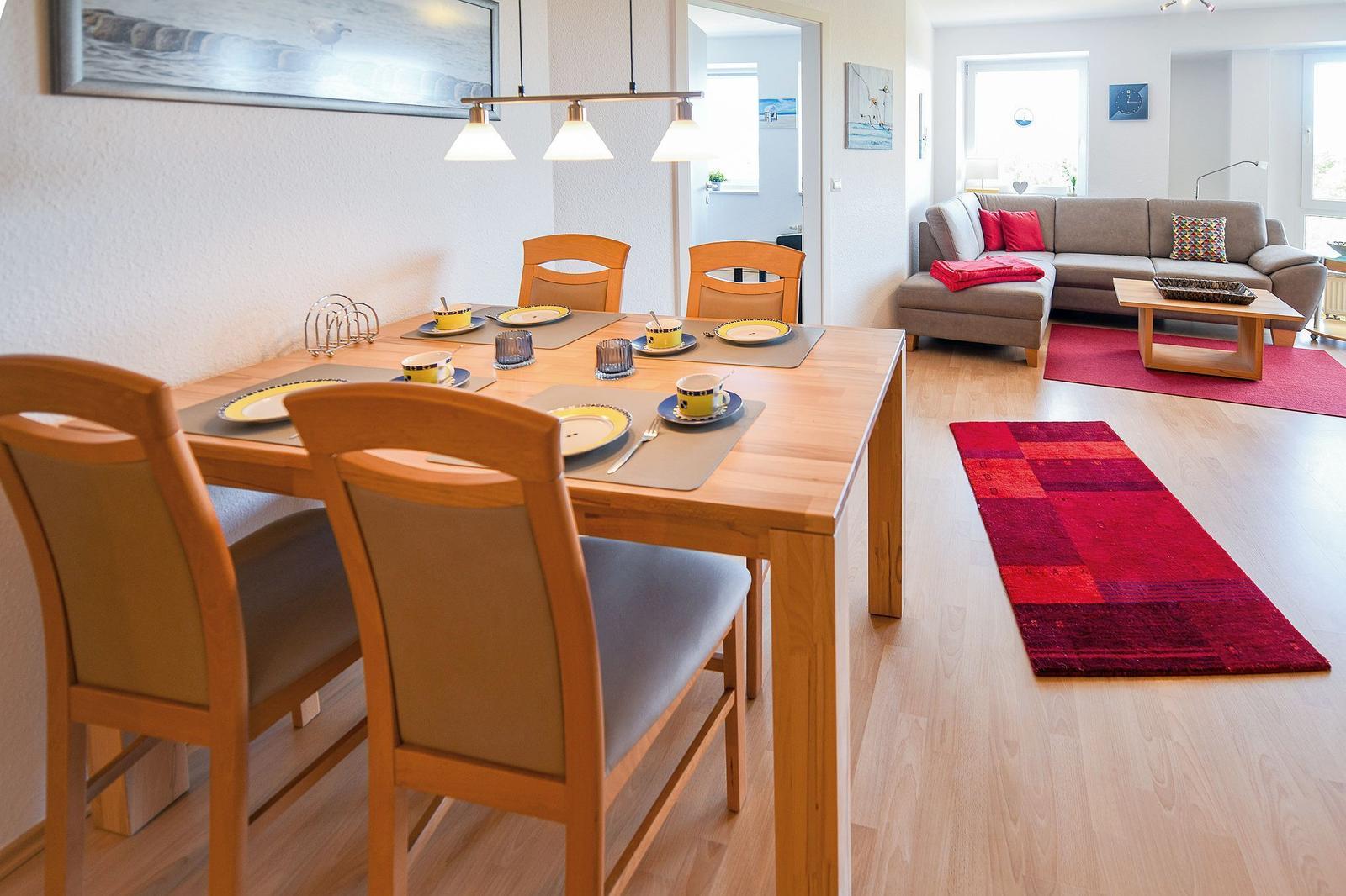 Essbereich mit Tisch und Stühlen. Wohnzimmer mit Sofa und Teppich.