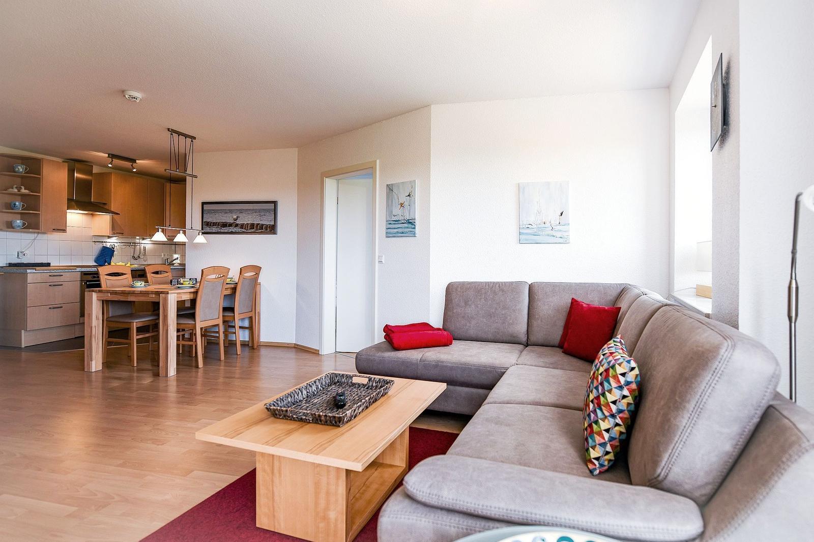 Wohnbereich mit Sofa, Couchtisch und Essbereich. Küche im Hintergrund.