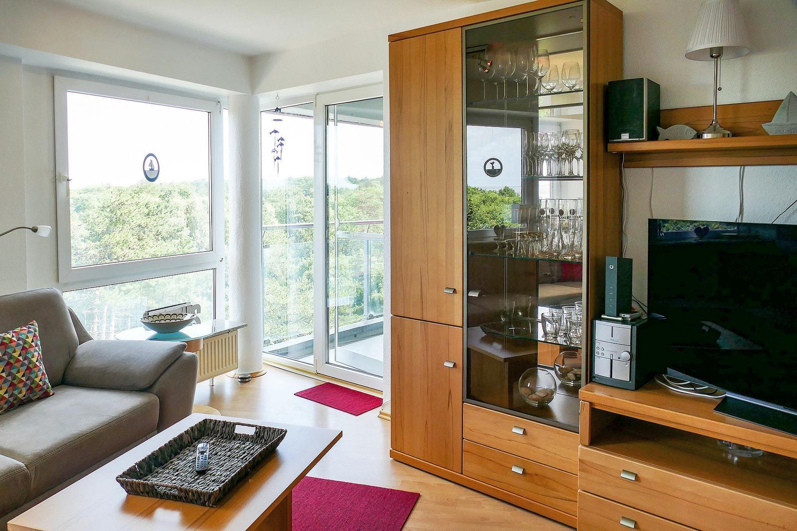 Wohnzimmer mit Sofa, Glaswand, TV und Holzmöbel