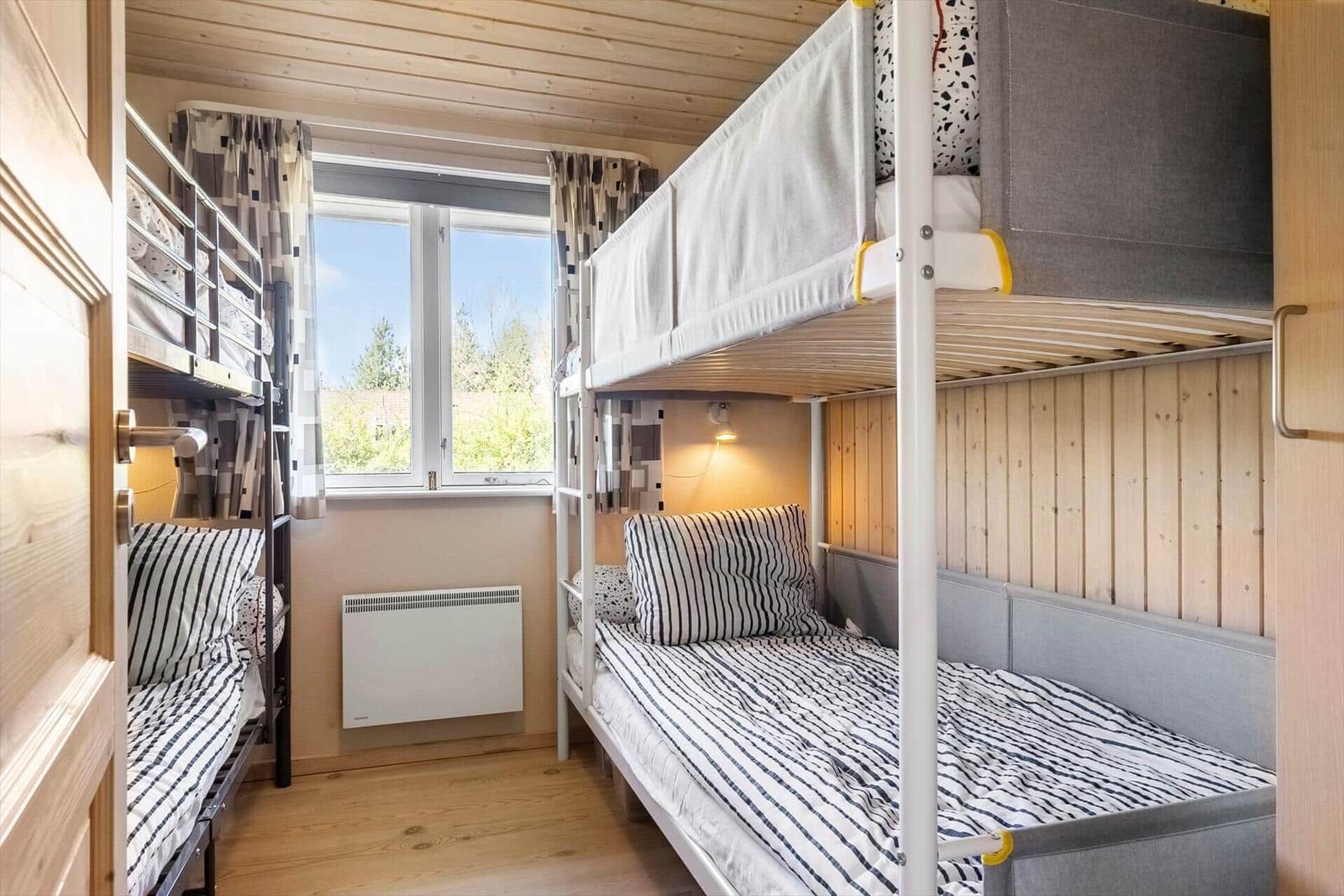 Zimmer mit zwei Stockbetten, Fenster und Heizung.