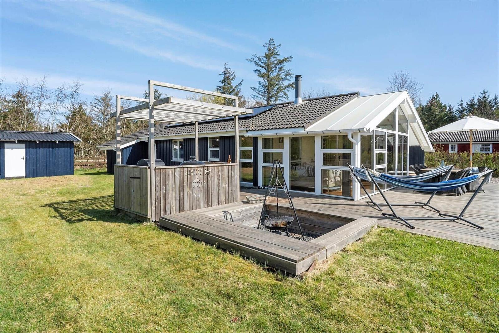 Haus mit Terrasse, Hängematten und Grillplatz im Garten.