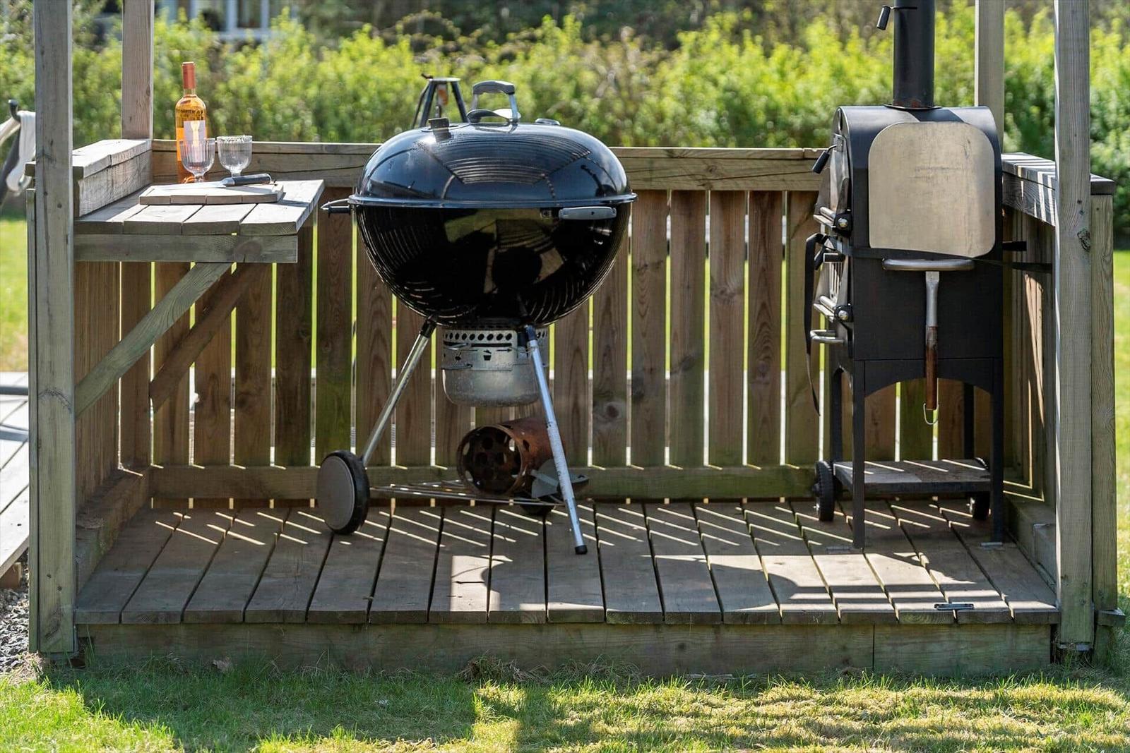 Außenbereich mit Grill und Ofen auf Holzterrasse.