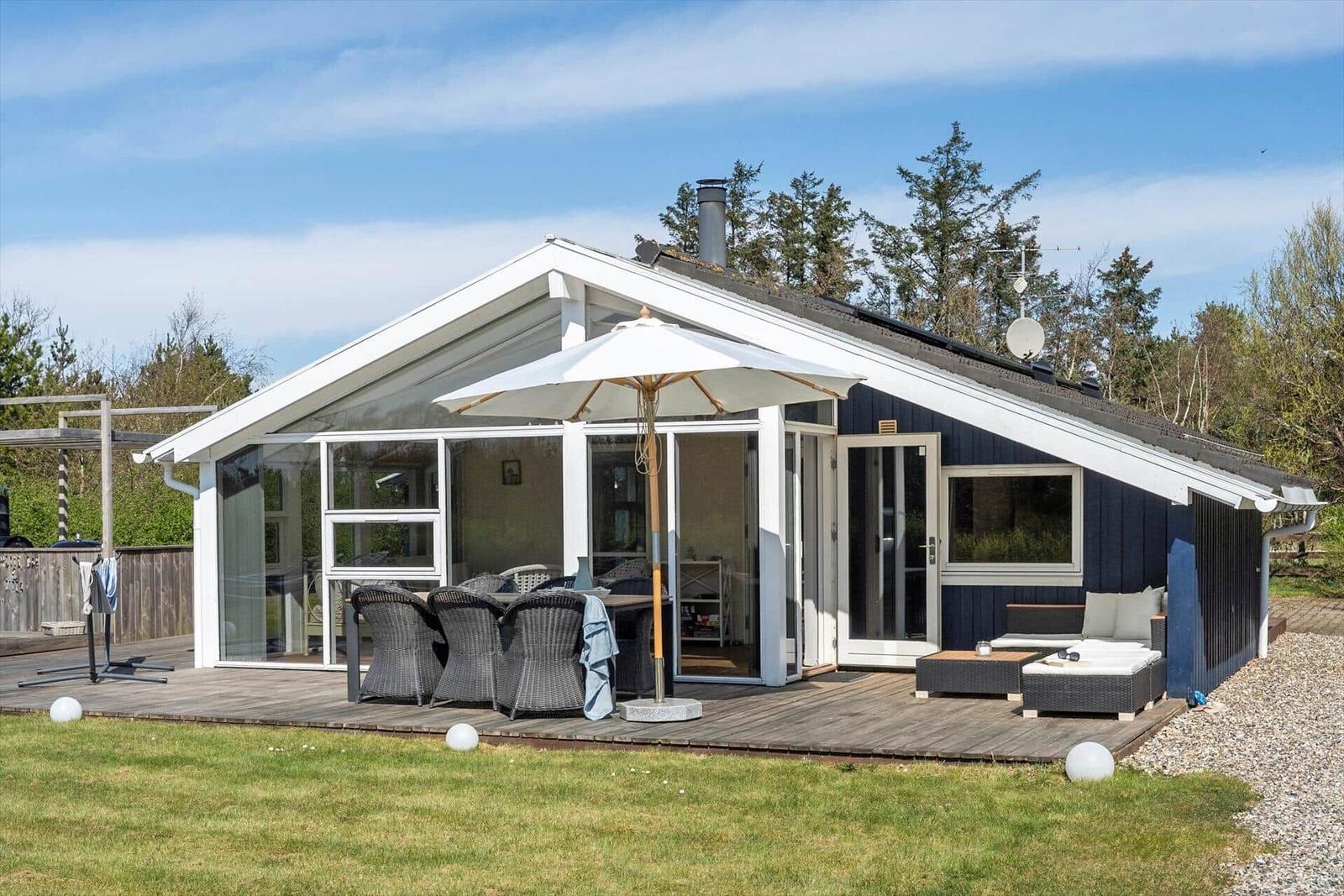Moderne Villa mit Terrasse, Sonnenschirm und Garten. Holzterrasse mit Sitzgelegenheiten.