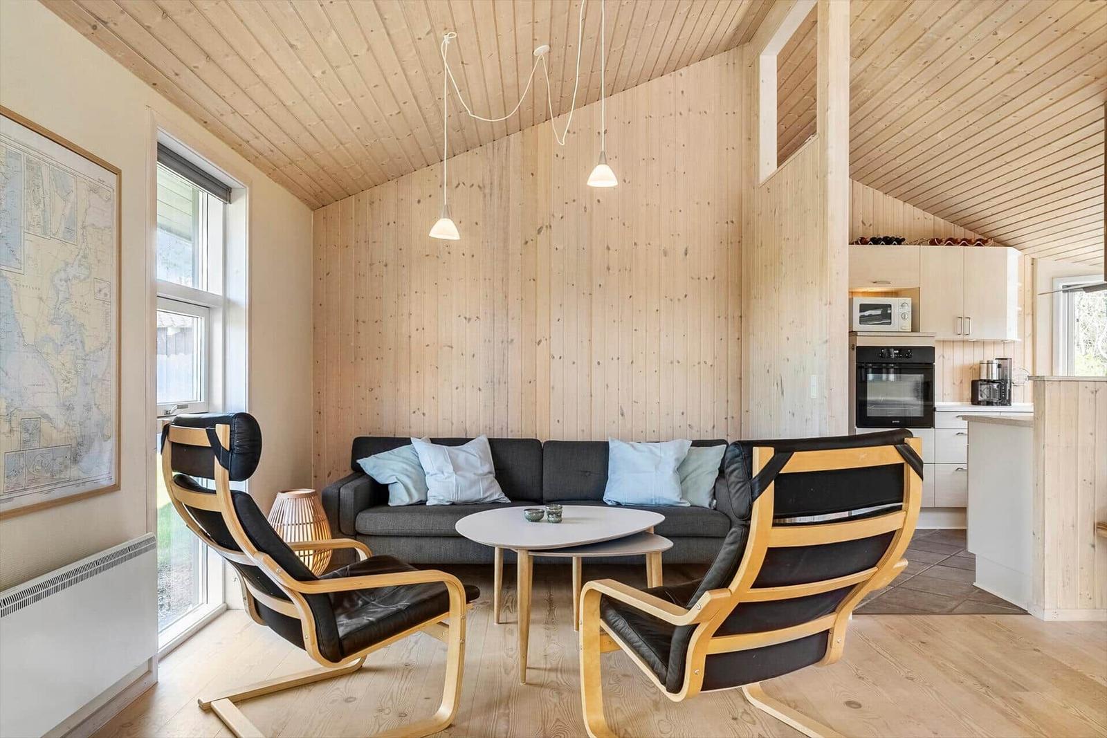 Wohnbereich mit Sofa, zwei Sessel und Küchenzeile