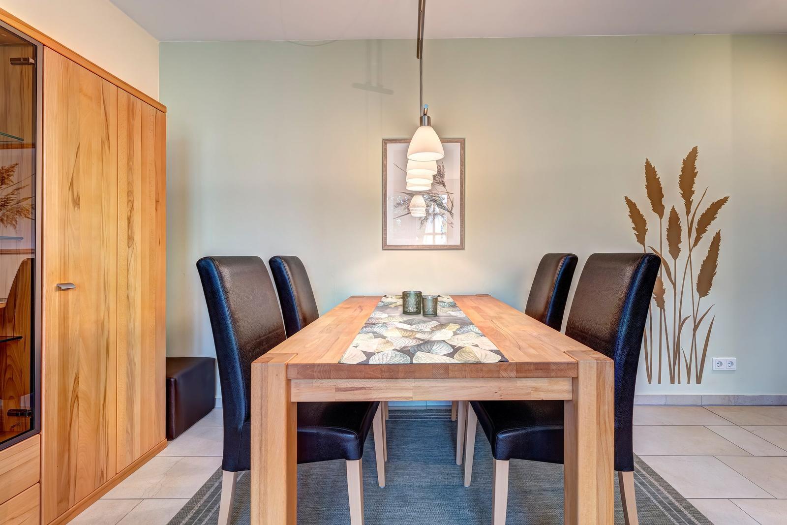 Esszimmer mit Holztisch, sechs Stühlen und Wanddekoration.