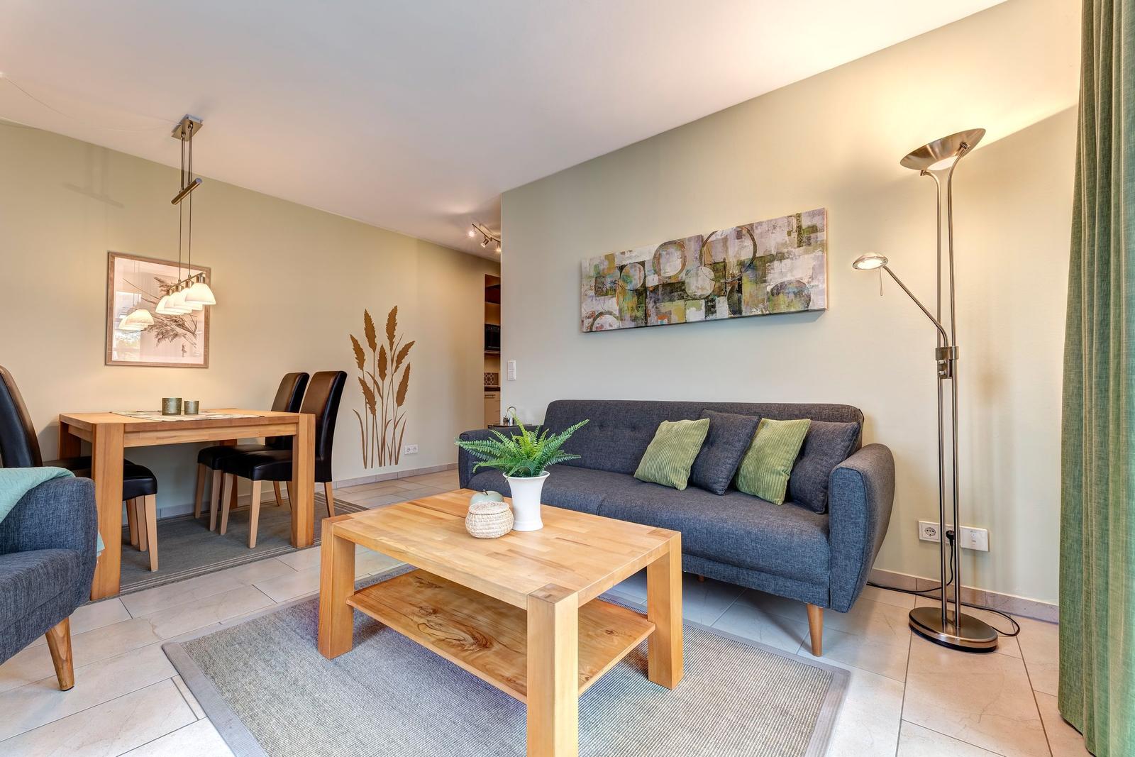 Wohn- und Essbereich mit Sofa, Tisch und Wandbild.