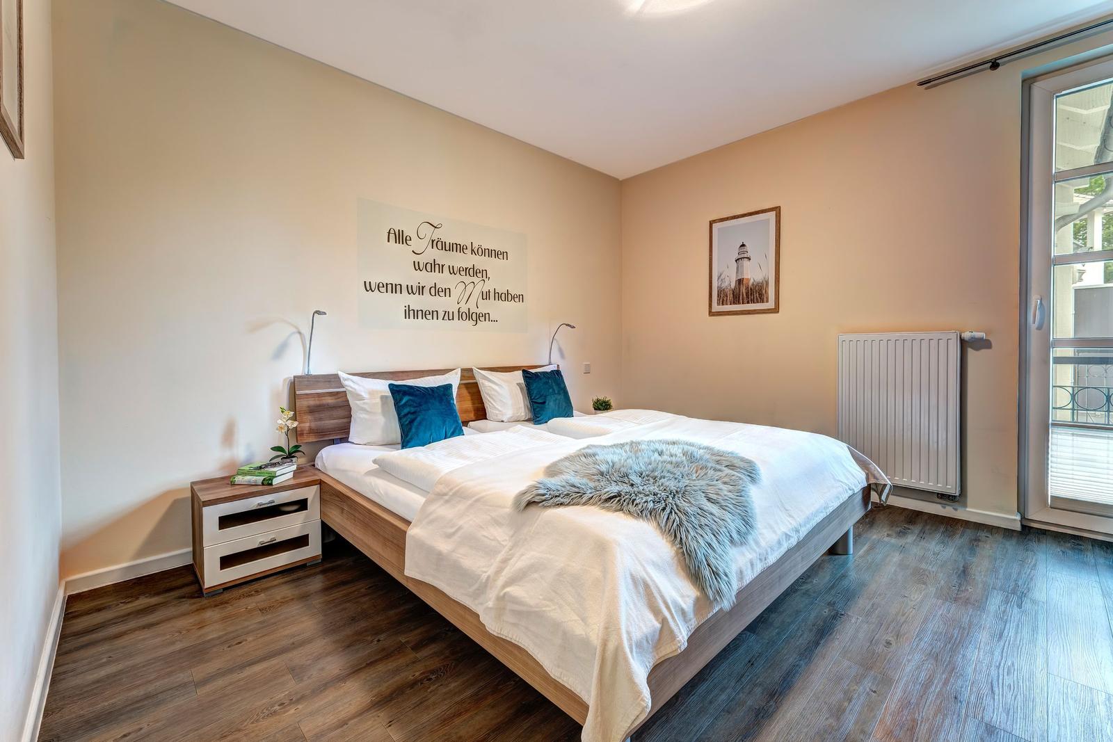 Schlafzimmer mit Doppelbett, Wanddekoration und Terrassentür.