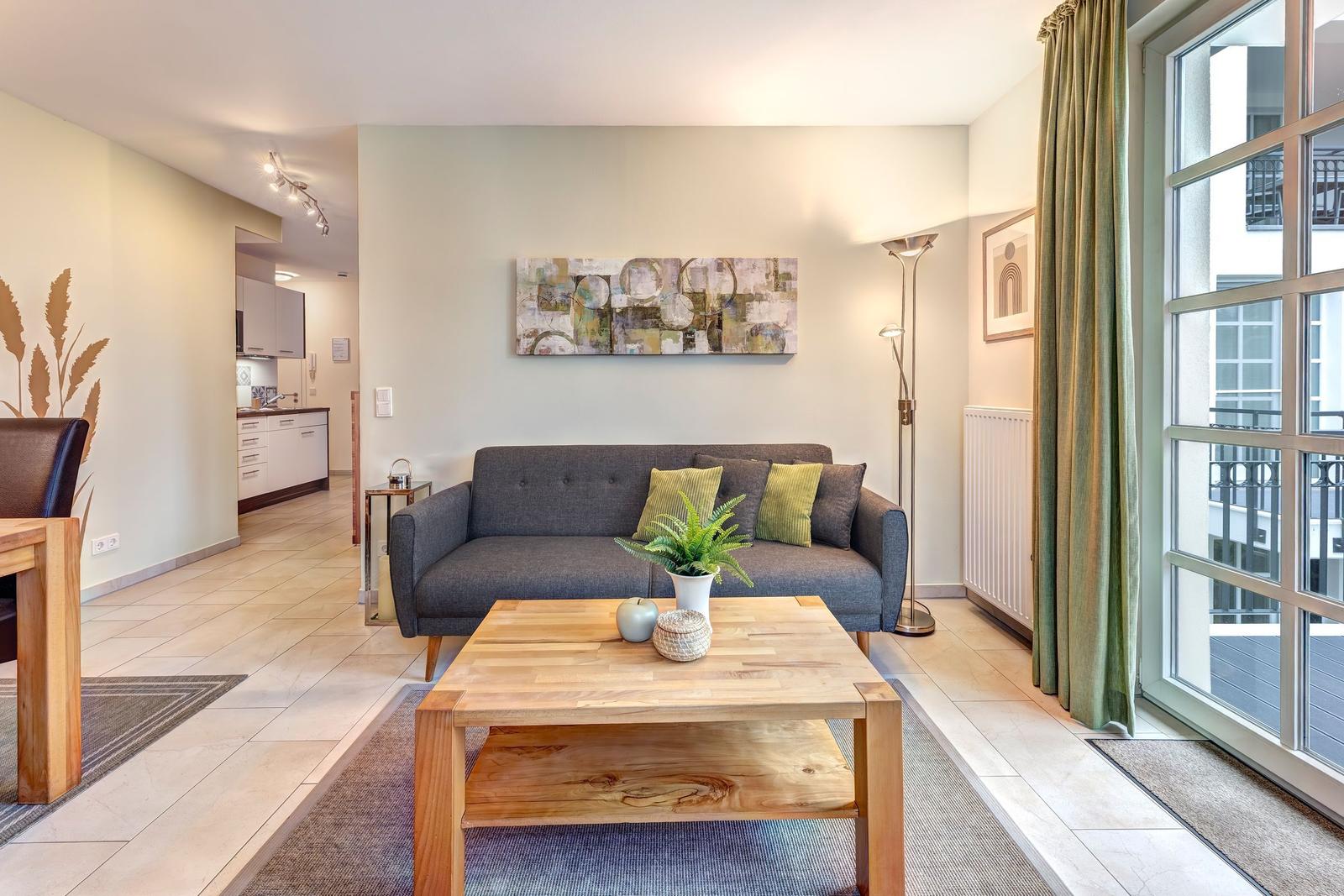 Wohnzimmer mit Sofa, Couchtisch und Blick auf Balkon.