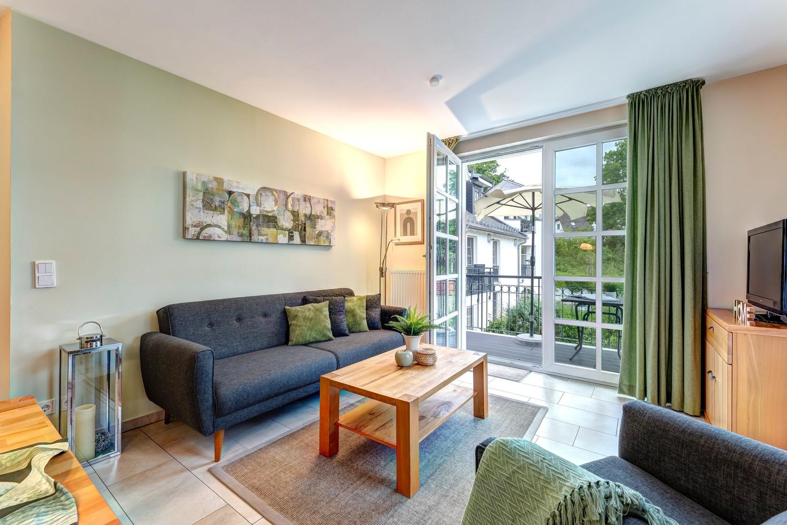 Wohnzimmer mit Sofa, Couchtisch und Balkonansicht