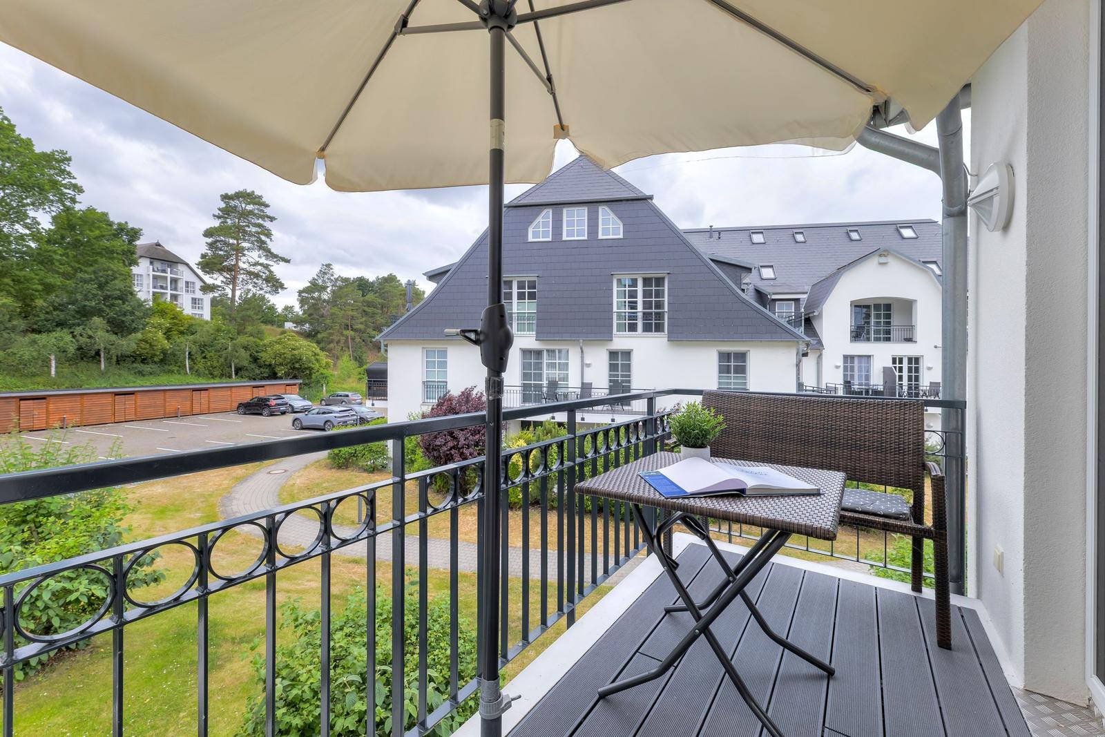 Balcony with table, chair, and umbrella overlooking a residential area.