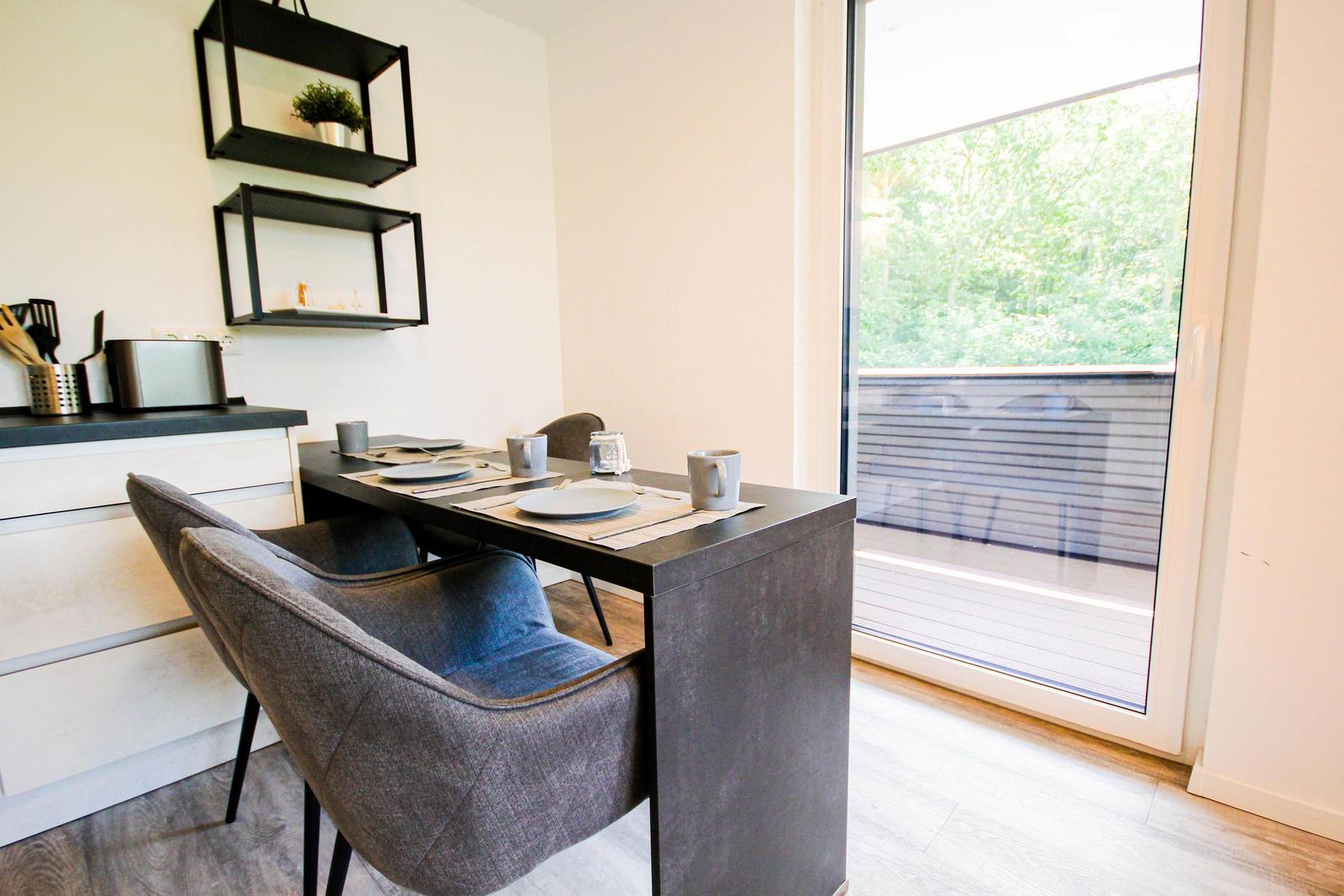 Essbereich mit Tisch und Stühlen, große Fensterfront mit Blick auf Balkon.