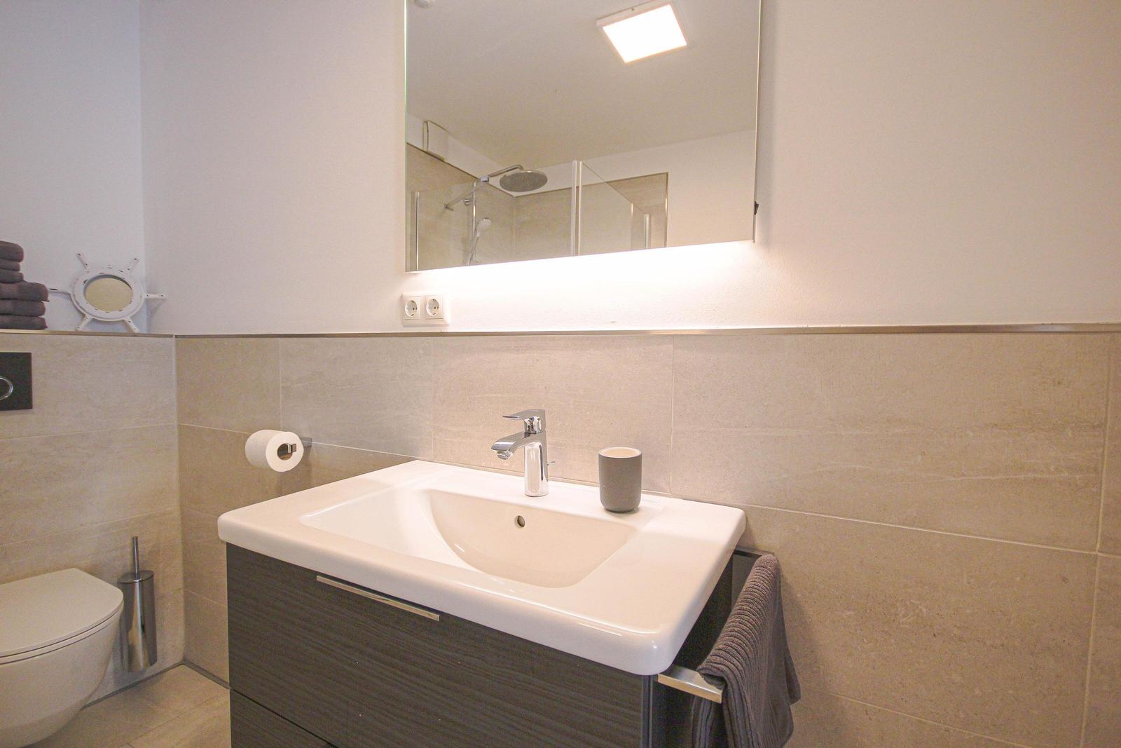 Badezimmer mit Waschbecken, Spiegel und Dusche.