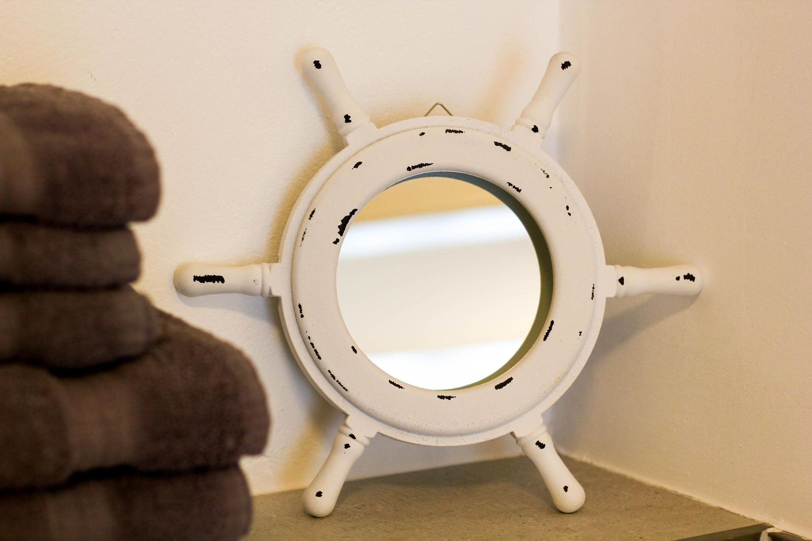 Spiegel im Stil eines Schiffsruders mit weißen Armaturen und dunklen Flecken.