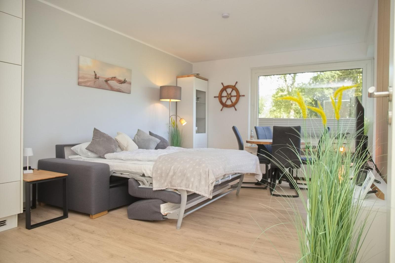 Schlafzimmer mit Schlafcouch, Tisch und Stühlen, Wandbild und Segelruder.