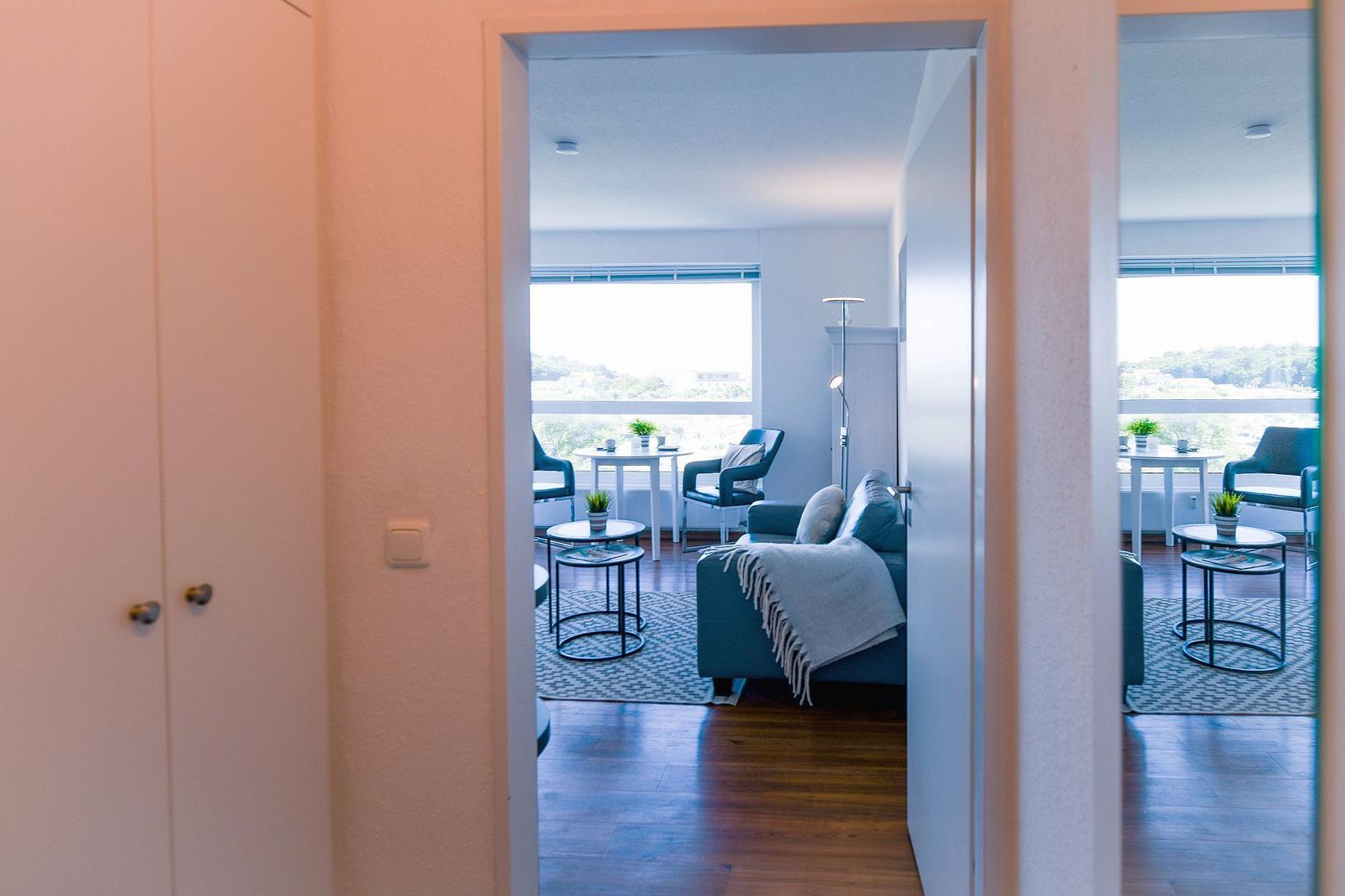 Wohnbereich mit Sofa, Tischen und Blick auf Balkon