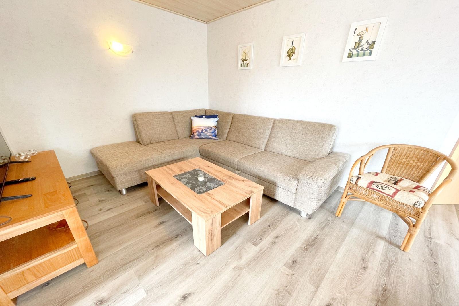 Wohnzimmer mit Sofa, Couchtisch und Stuhl. Wandbilder und Holzboden.