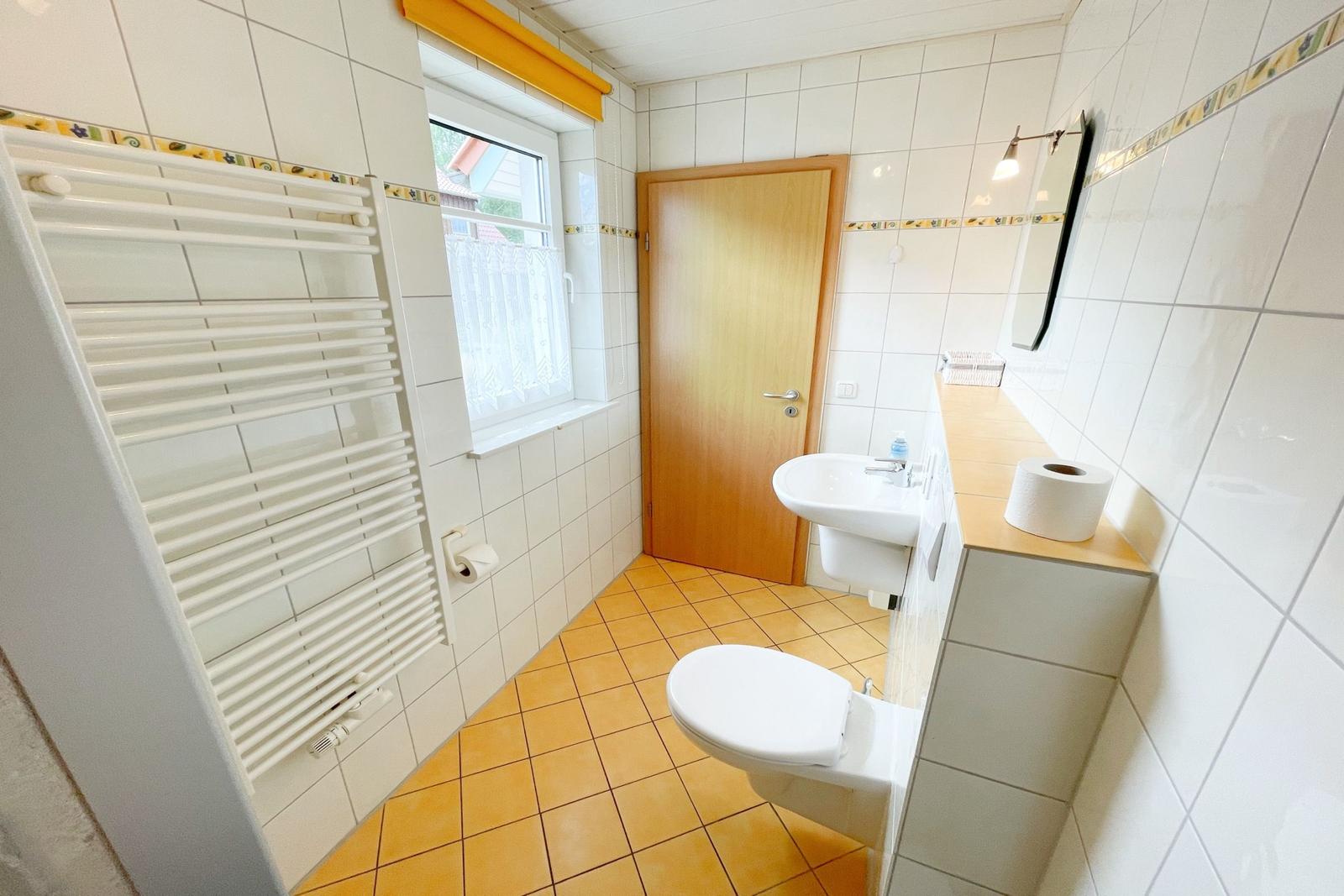 Badezimmer mit Toilette, Waschbecken und Heizkörper an der Wand.