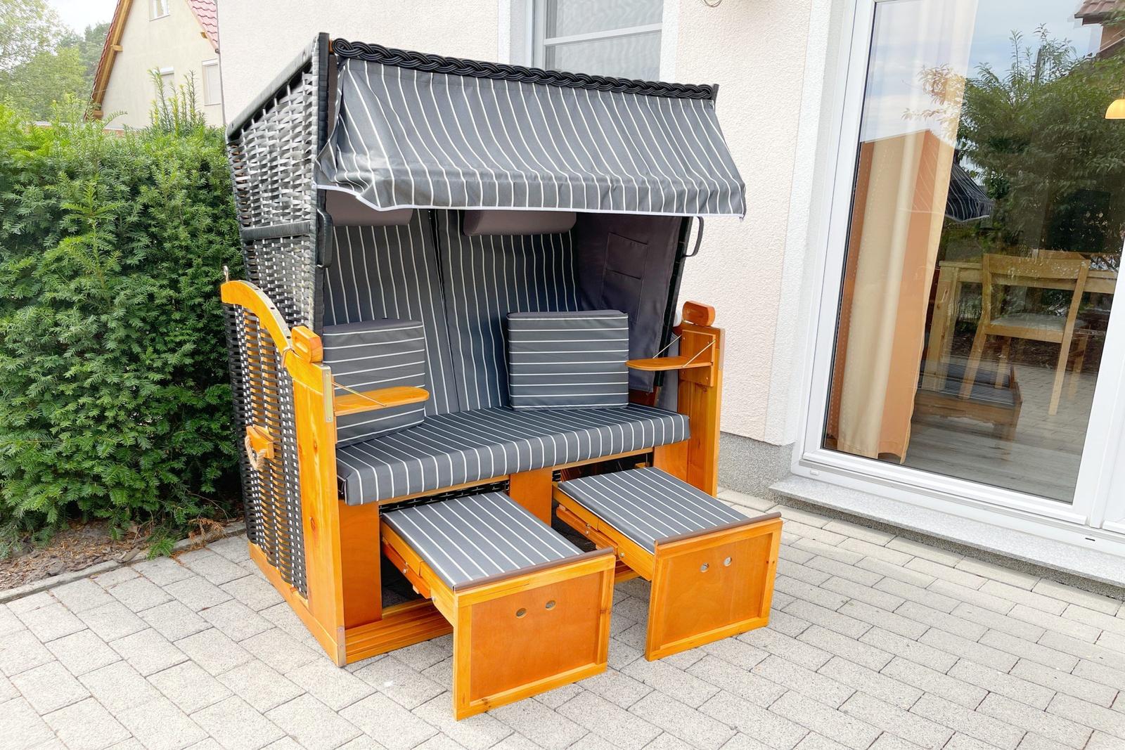 Hochwertiger Strandkorb mit Schutzdach und Sitzbänken auf Terrasse.