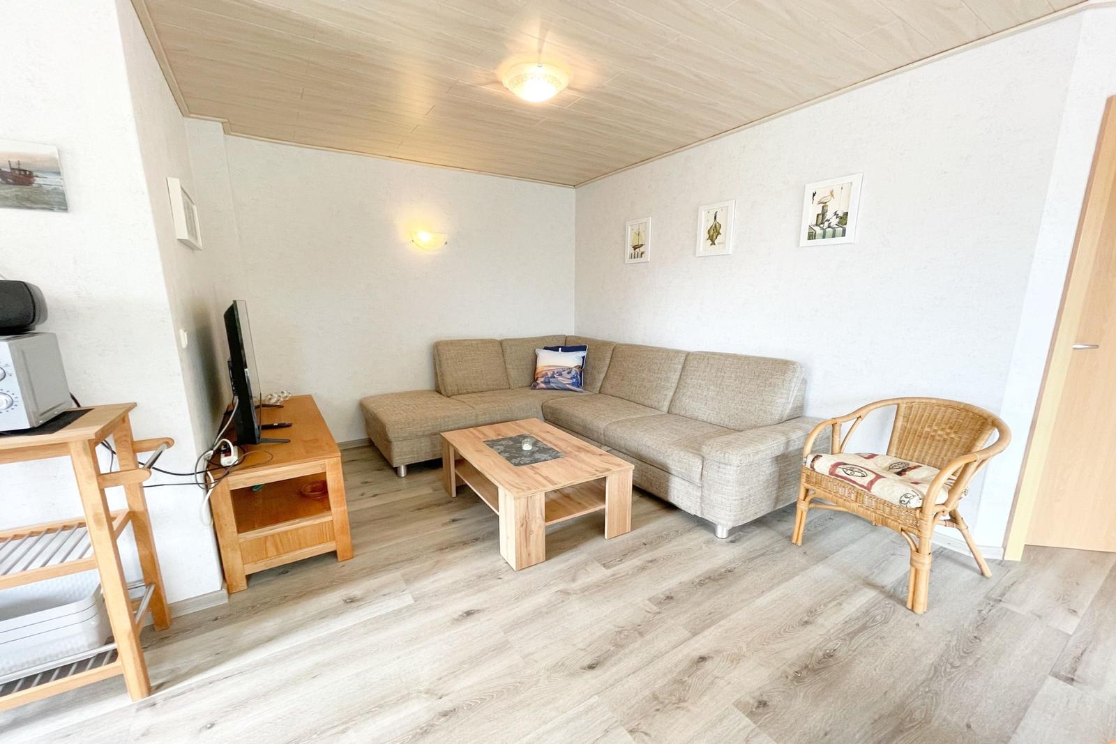 Wohnzimmer mit Sofa, Couchtisch und Stuhl. Holzboden und -decke. Wandbilder.