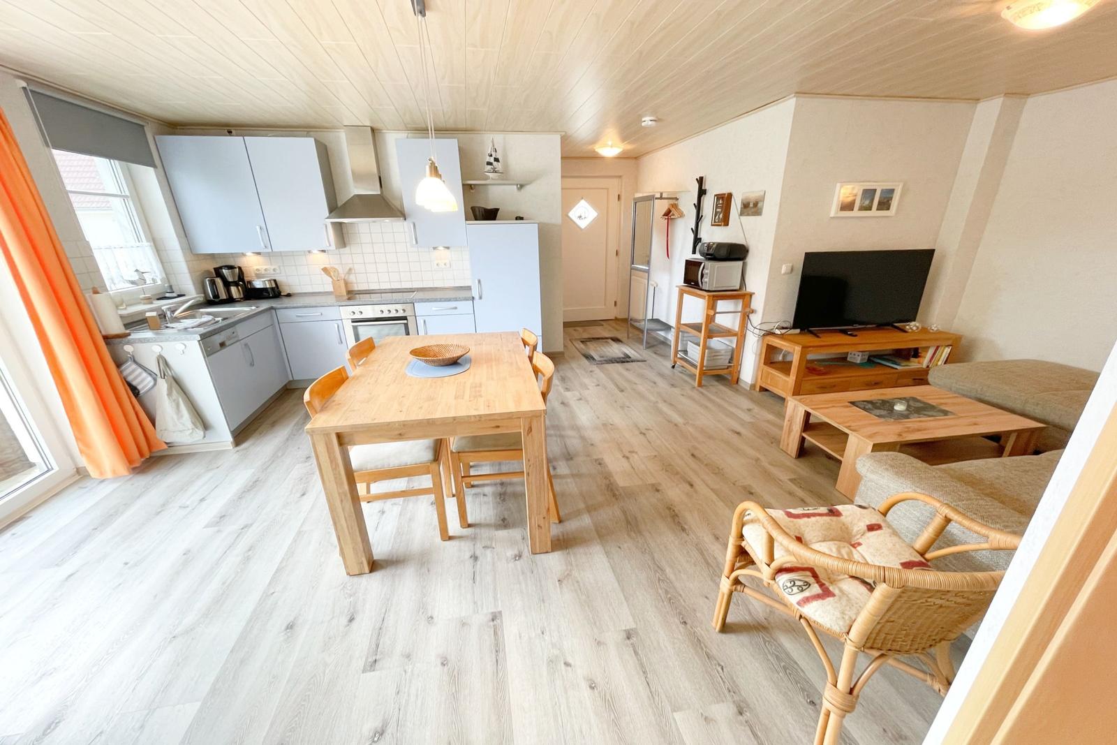 Küche, Essbereich und Wohnzimmer mit Holzboden und hellen Wänden.