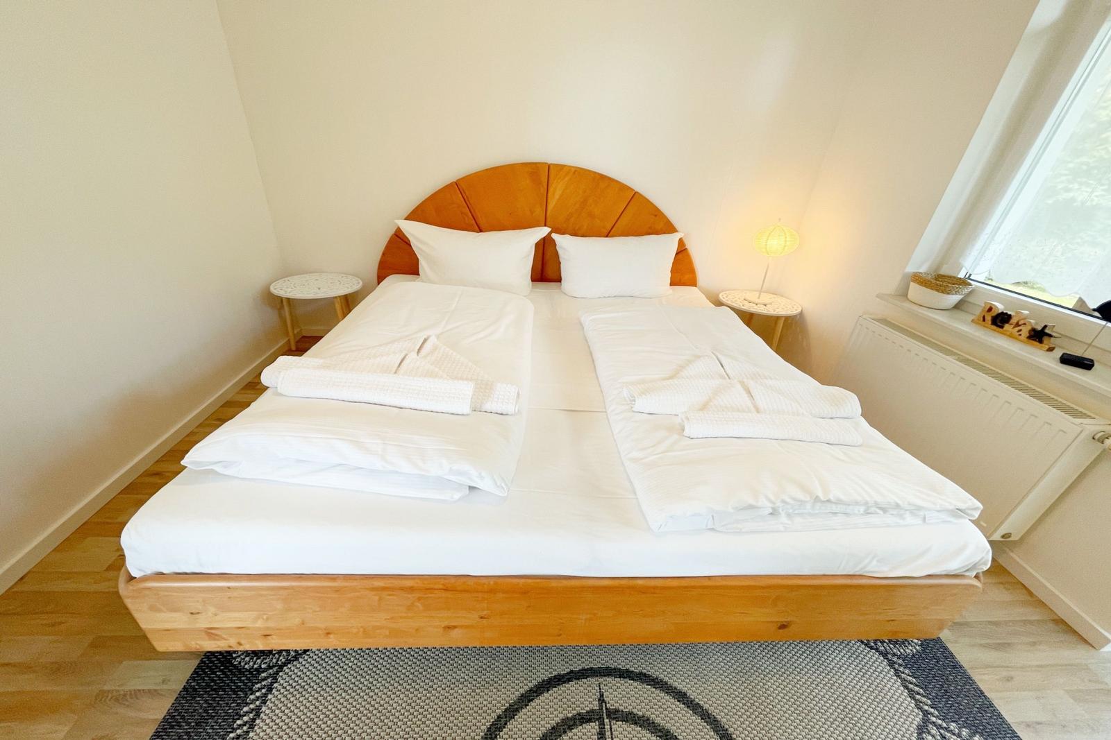 Schlafzimmer mit Doppelbett, Holzboden und Fenster.