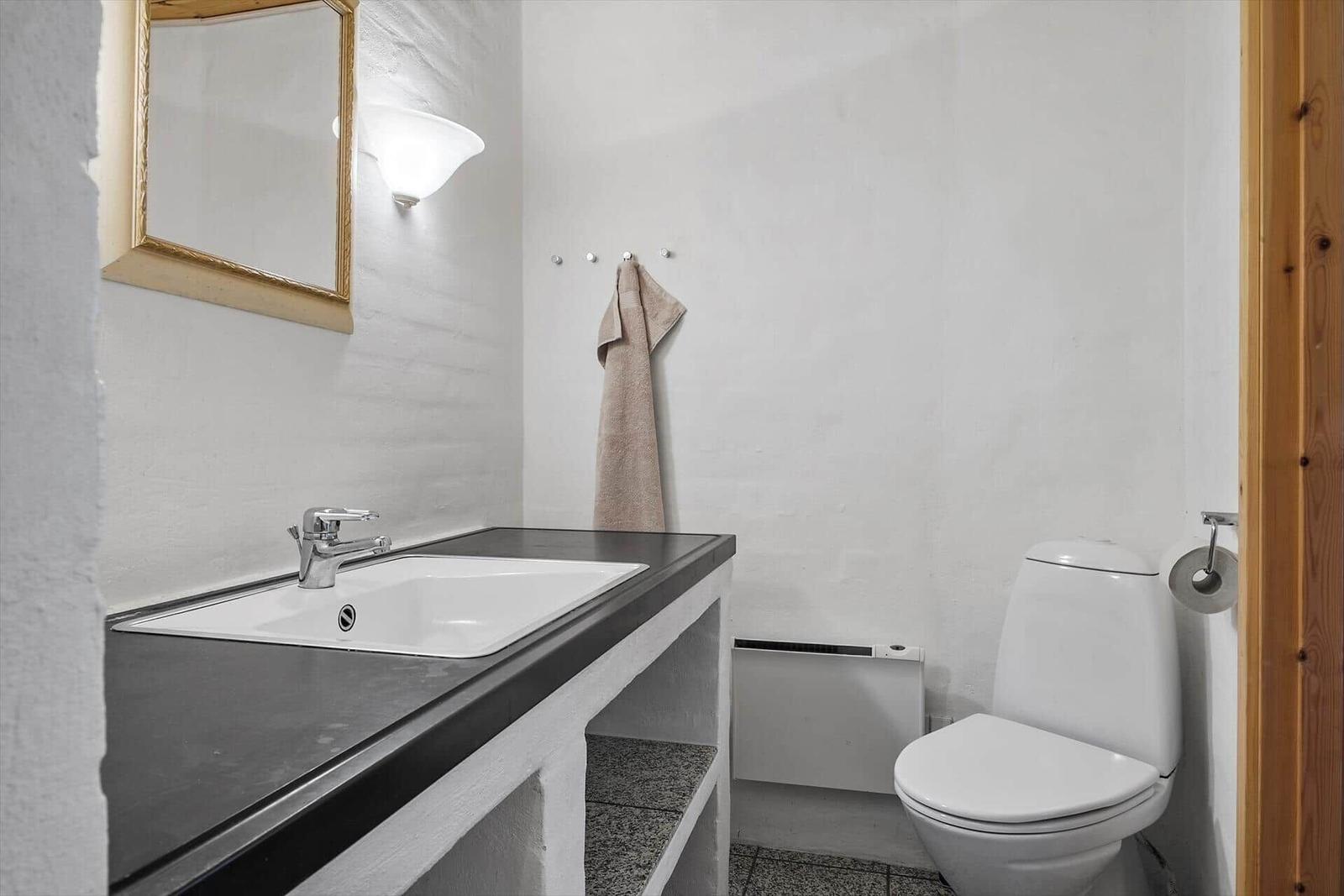 Badezimmer mit Waschbecken, Spiegel, Toilette und Handtuch.