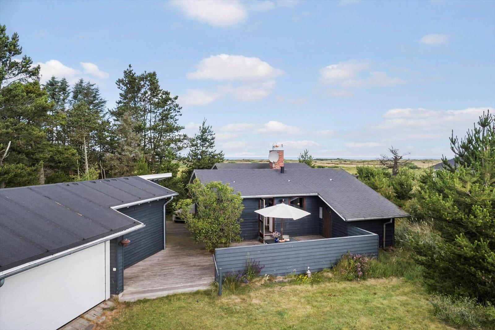 Moderne Villa mit Terrasse, Grill und Garten. Umgeben von Bäumen und Gras.