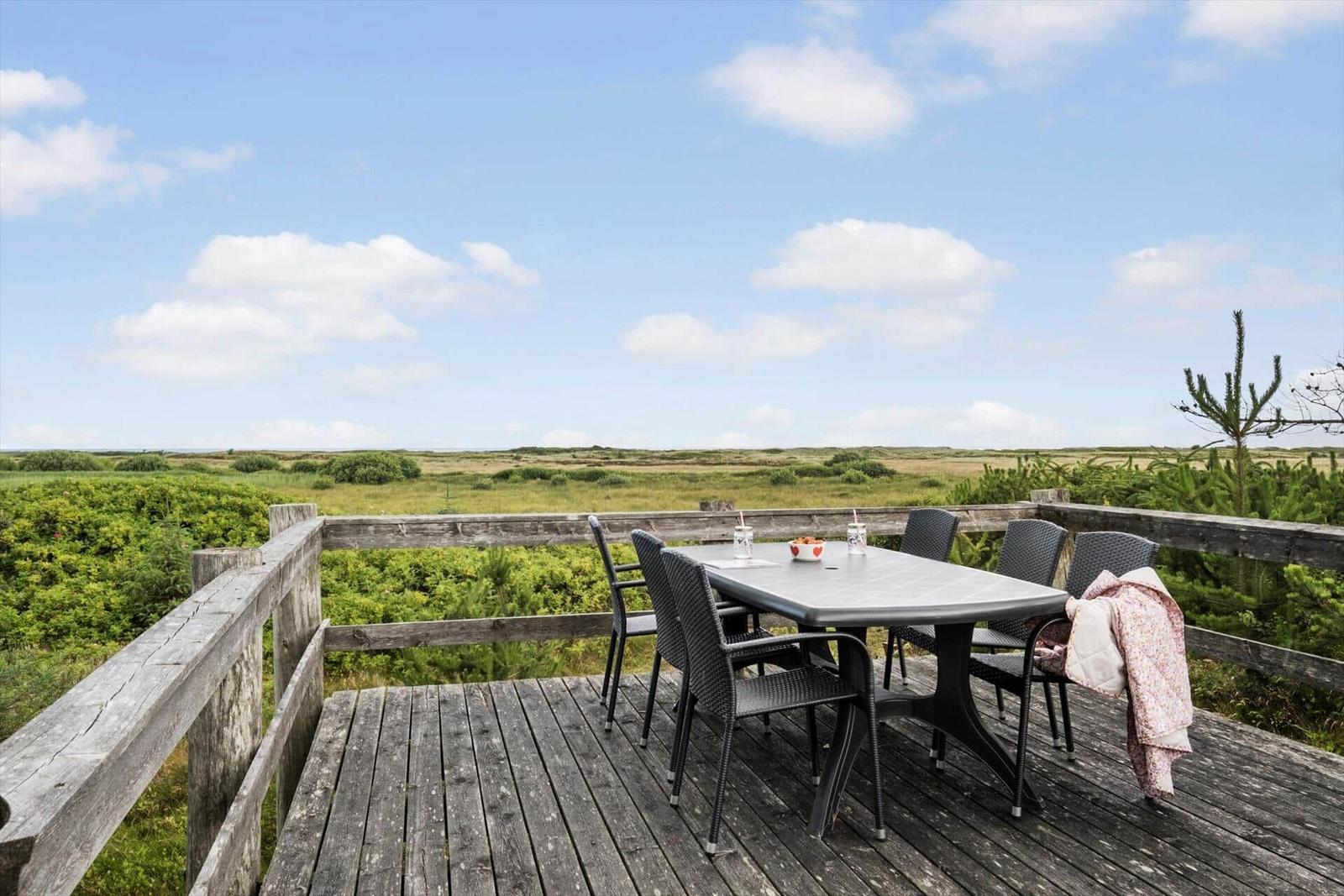 Terrasse mit Tisch und Stühlen bietet Blick auf Grünland.