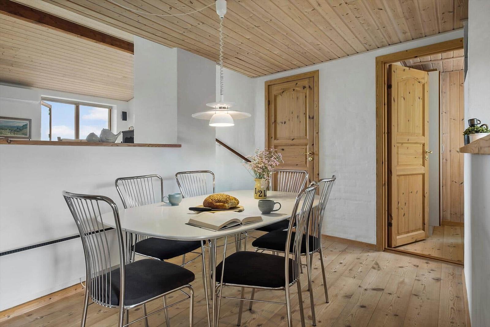 Esszimmer mit Holzboden, Tisch und Stühlen, Fenster und Tür.