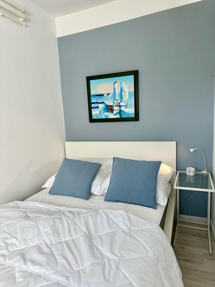 Schlafzimmer mit Bett, Wandbild und Nachttisch.