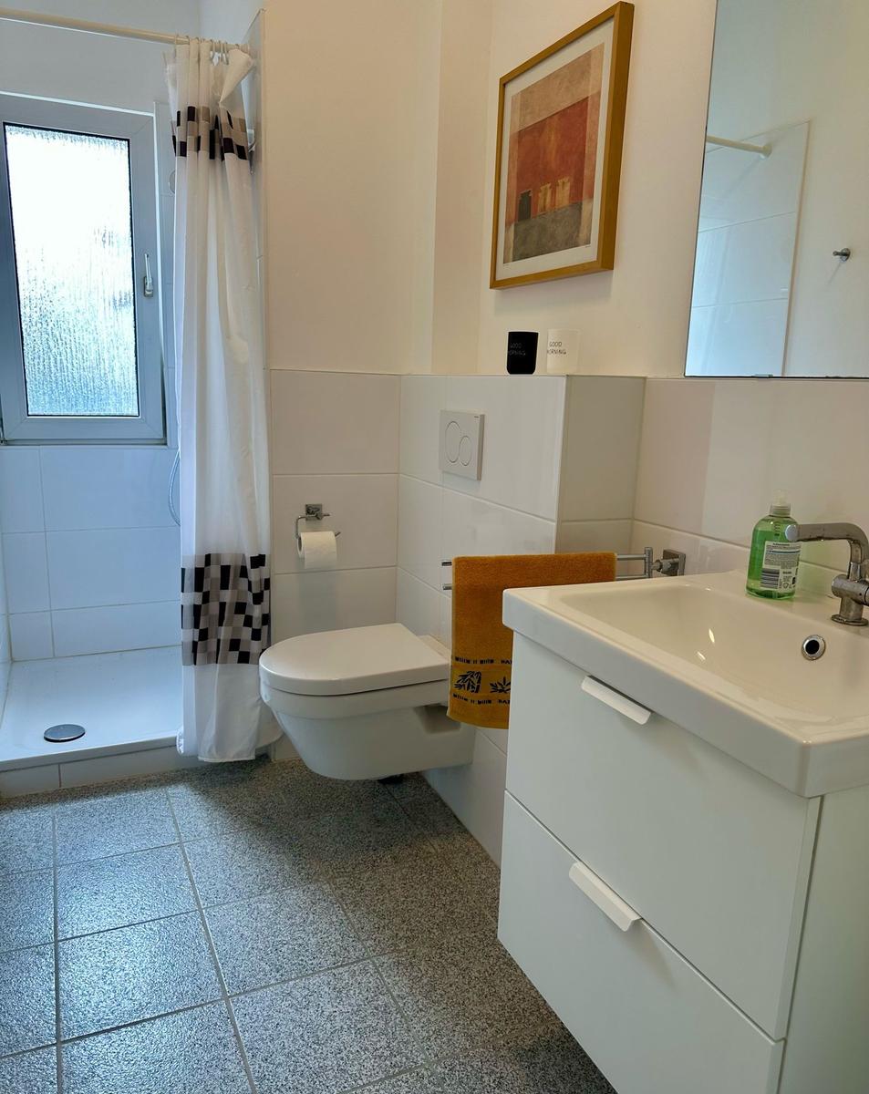 Badezimmer mit Dusche, Toilette und Waschbecken mit Spiegel.