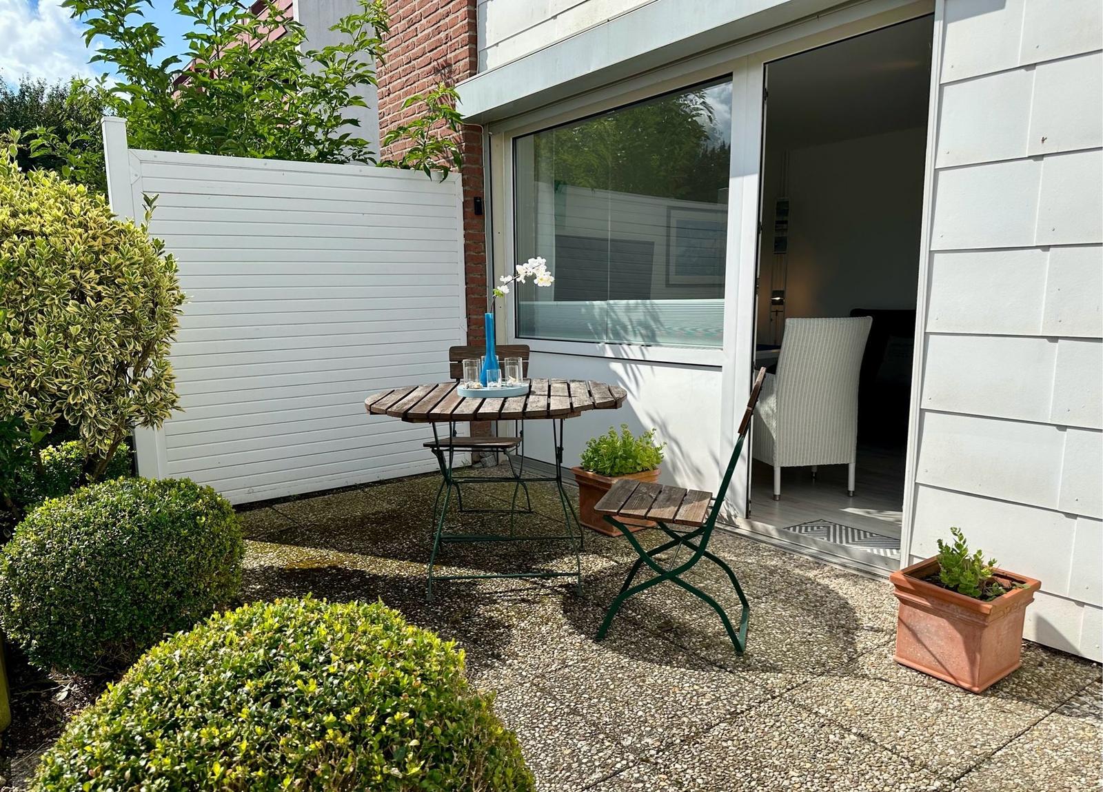 Hinterhof mit Tisch, Stühlen und Pflanzen. Durchgang ins Innere.