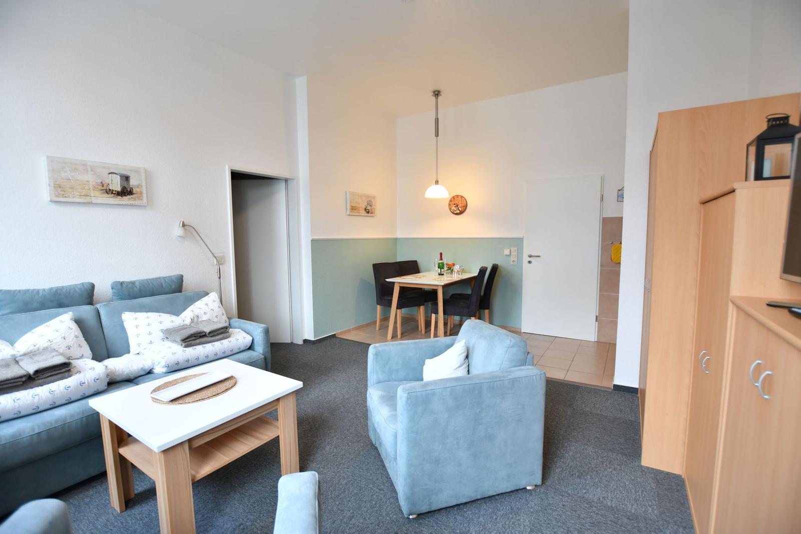 Wohn- und Essbereich mit Sofa, Sessel, Tisch und Stühlen.