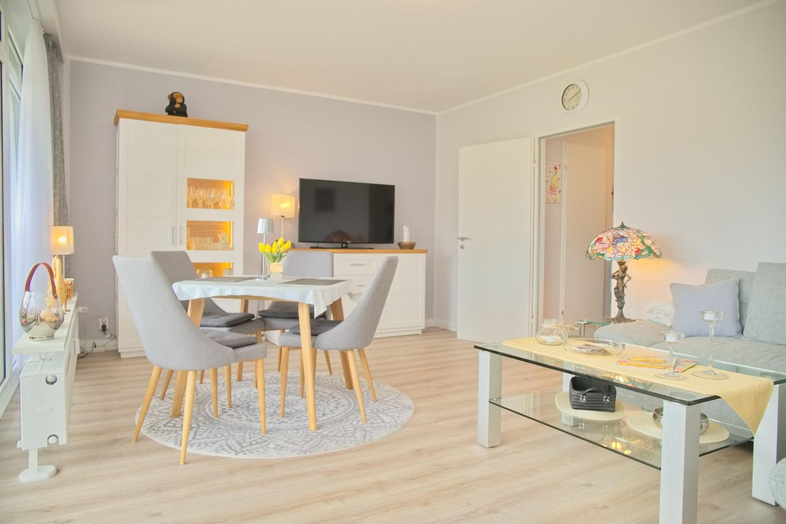 Wohn- und Essbereich mit Sofa, Esstisch und Fernseher.