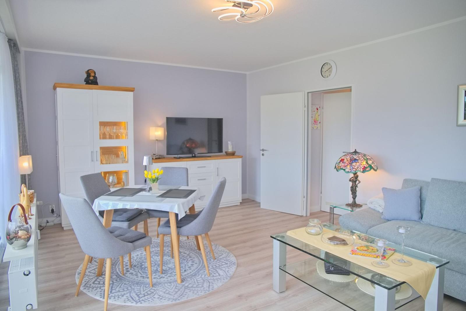 Wohn- und Essbereich mit Sofa, Esstisch und Fernseher.